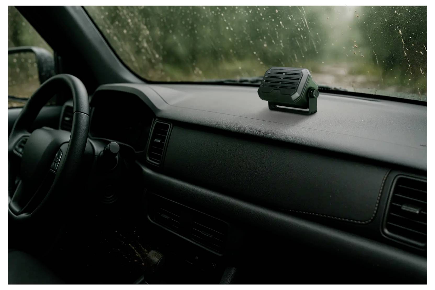 Innenraum eines Autodashboards mit einem kleinen elektronischen Gerät, das in der Nähe der Windschutzscheibe montiert ist, fotografiert unter regnerischen Bedingungen.