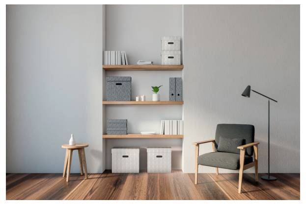 Minimales modernes Wohnzimmer mit grauem Sessel, Stehleuchte, Holzregalen, Aufbewahrungsboxen und kleinem Beistelltisch auf Hartholzboden.