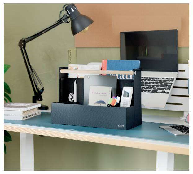 Schreibtischarbeitsbereich mit Laptop, schwarzer Lampe und Organizer, der Bücher und Büromaterialien hält.
