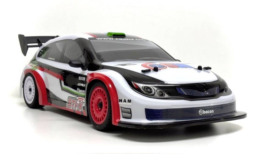 Ein Rennwagen-Modell mit einer weiß, schwarz, rot und grün gefärbten Lackierung, großem Heckflügel und roten Rädern auf einem schlichten weißen Hintergrund.