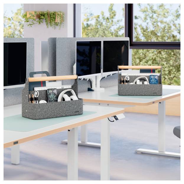 Modernes Open-Space-Büro mit weißen Schreibtischen, Monitoren und grauen Schreibtischorganizern, die Schreibwaren und Kopfhörer halten, in der Nähe großer Fenster.