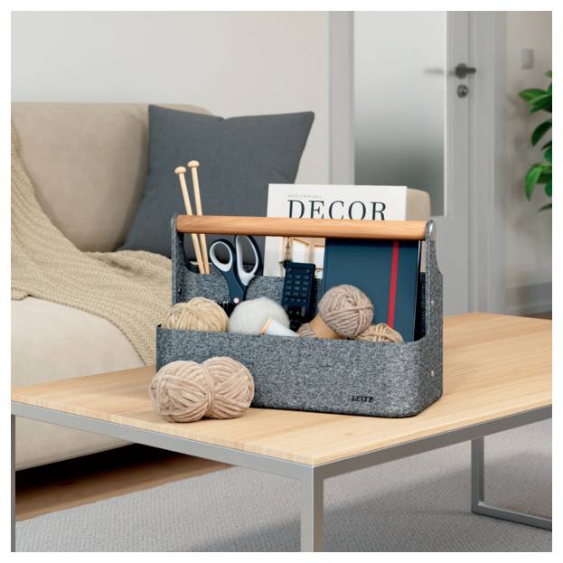 Grauer Stofforganizer auf einem Couchtisch enthält Strickmaterialien, Schere, Fernbedienung und eine „DECOR