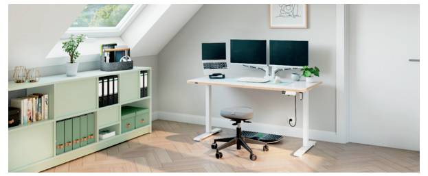 Helles Homeoffice mit einem Stehschreibtisch, Doppelmonitoren, Drehstuhl und mintgrünem Lagerschrank unter einer Dachschräge.
