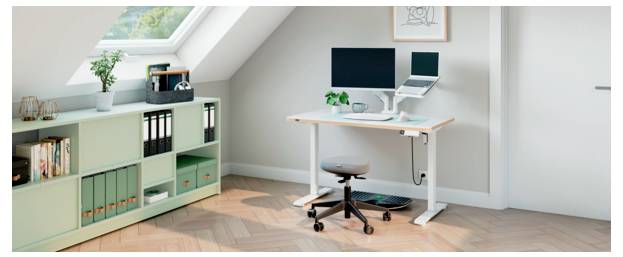 Minimales Homeoffice mit einem Schreibtisch, Computer, Drehstuhl, Aufbewahrungsschrank und Dachfenster in einem hellen Dachzimmer.