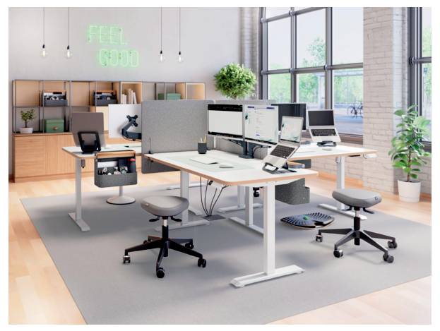 Modernes Großraumbüro mit Stehschreibtischen, Computermonitoren, Hockern, Topfpflanzen und einem Neon-Schild mit der Aufschrift „FEEL GOOD