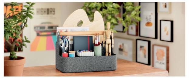 Ein Tischorganizer hält Bastelmaterialien, einschließlich Scheren, Stifte, Pinsel, Klebeband und Notizbücher, in einem hellen kreativen Arbeitsbereich.