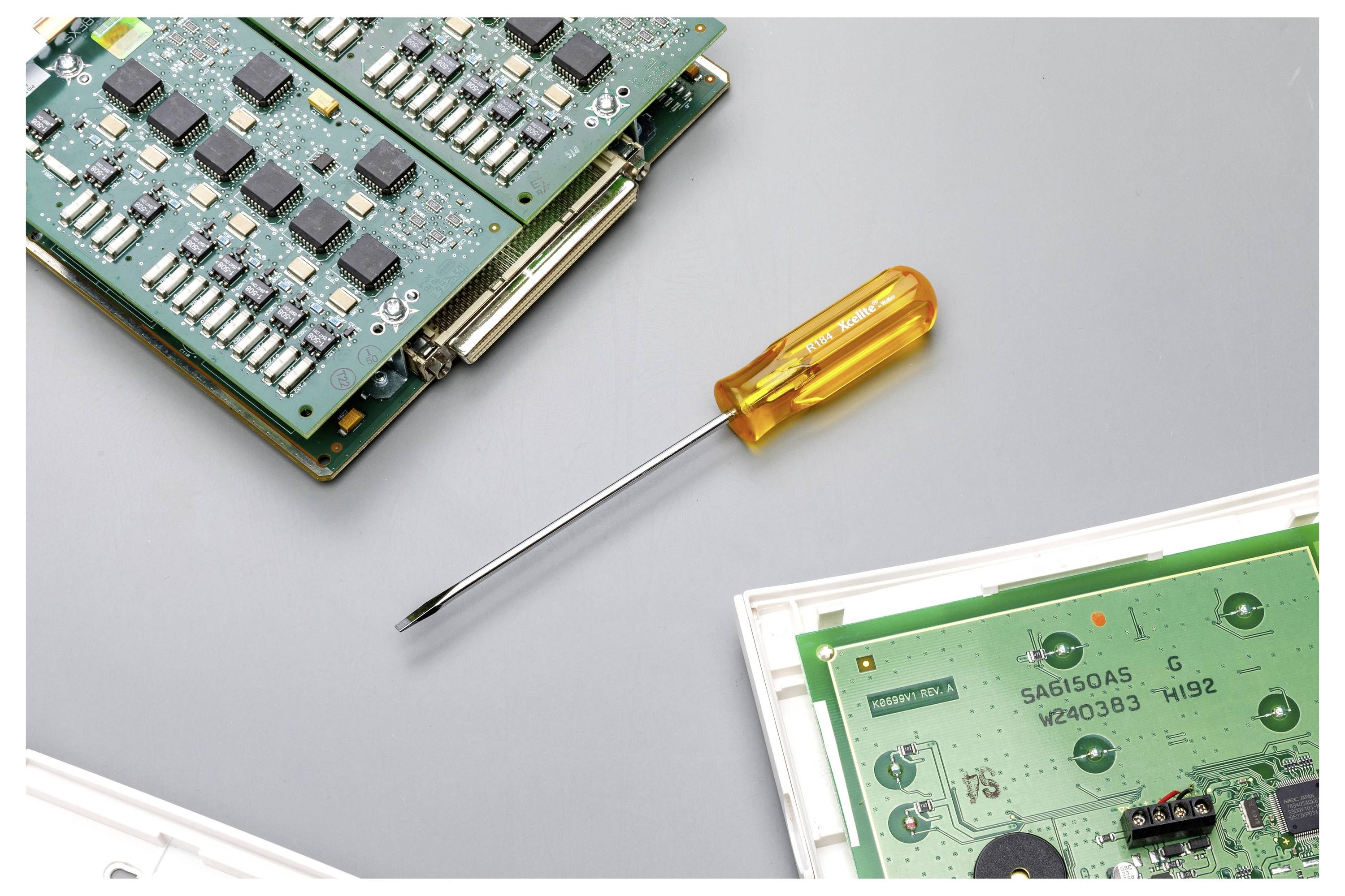Nahaufnahme von Leiterplatten und einem Schraubendreher, was auf Elektronikreparatur oder -montage hindeutet.