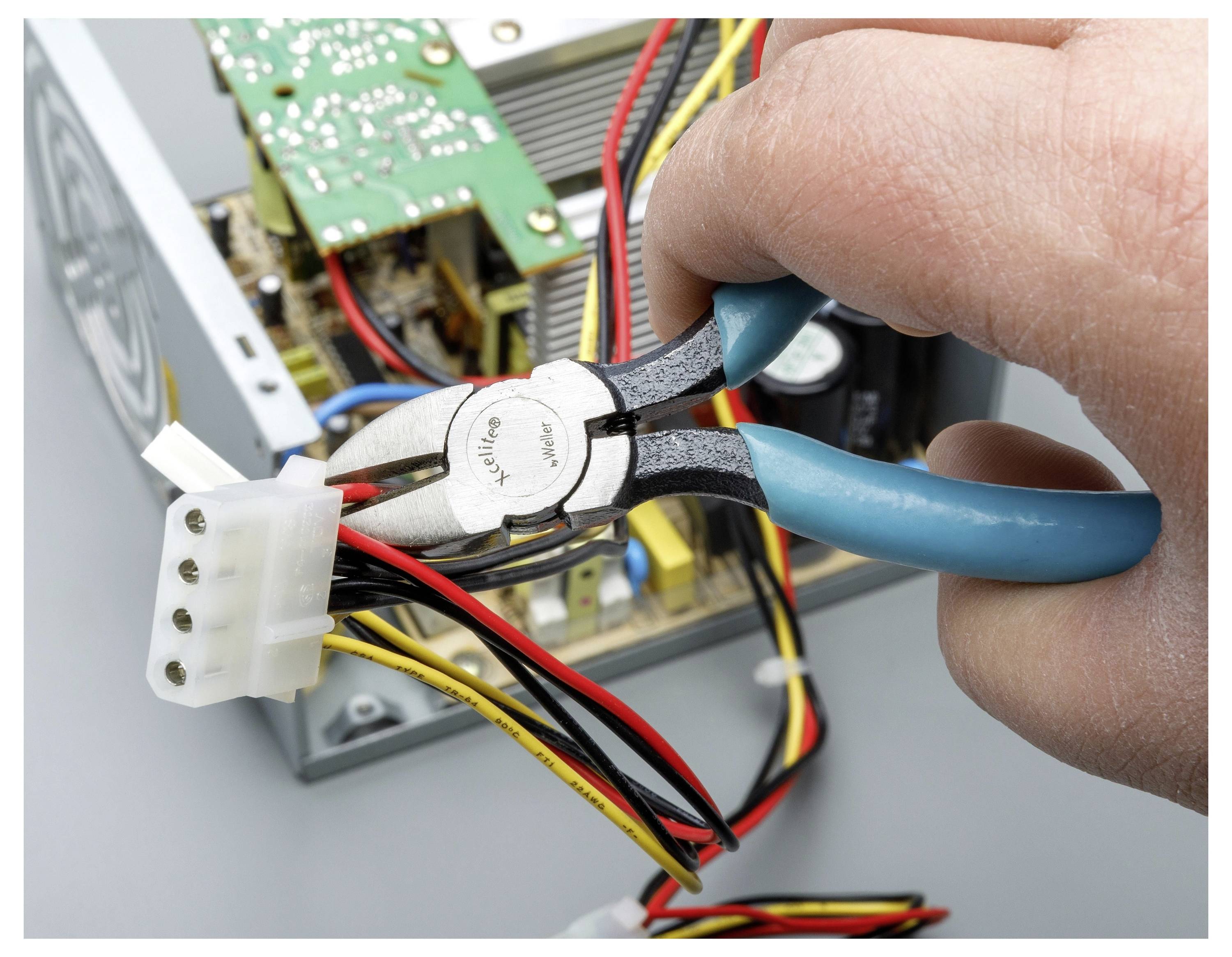Hand, die Zange hält, um Drähte an einem Computer-Stromstecker in einem offenen elektronischen Gerät zu durchtrennen.