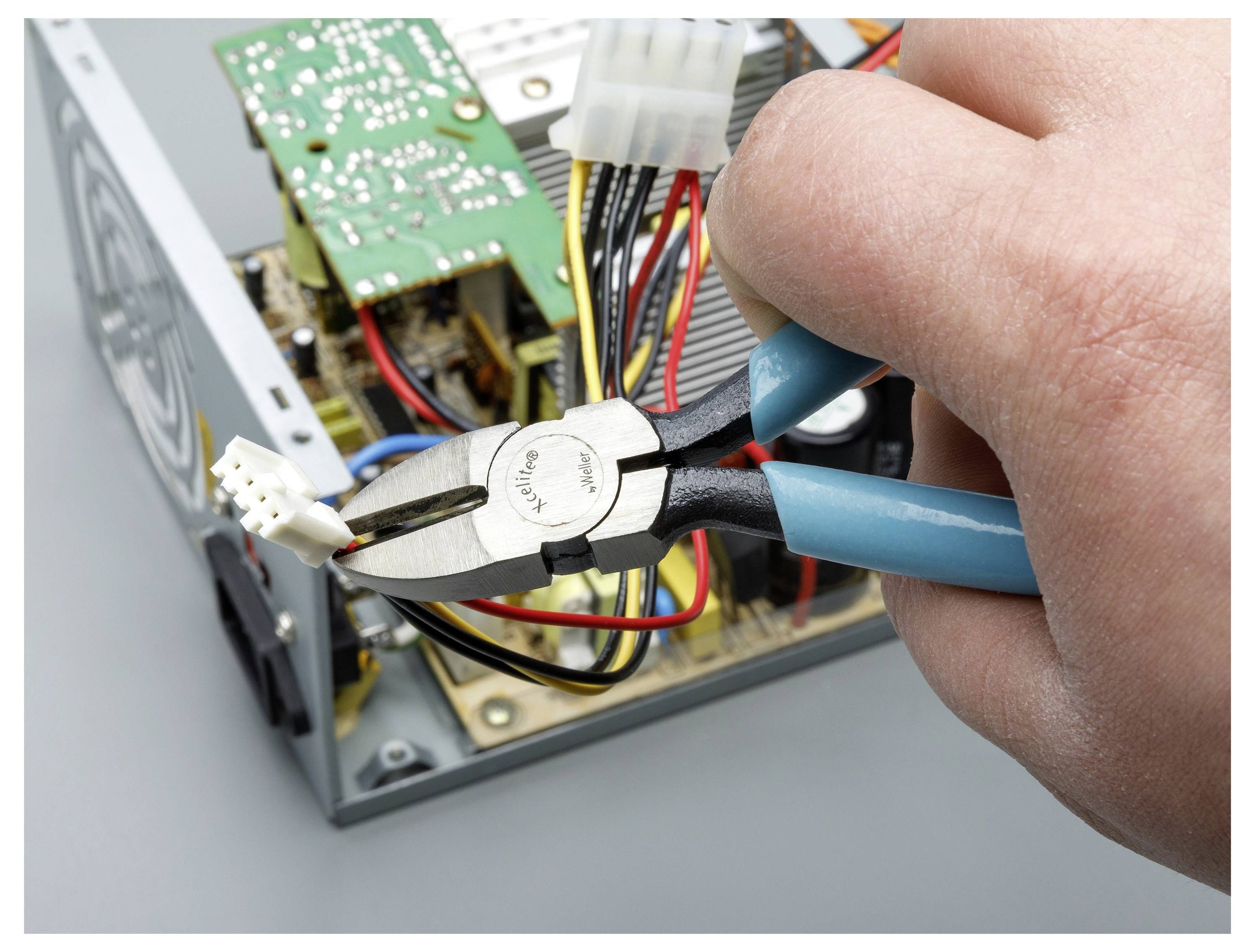 Hand mit Zange, die einen Draht in einem geöffneten elektronischen Gerät oder Computer durchschneidet