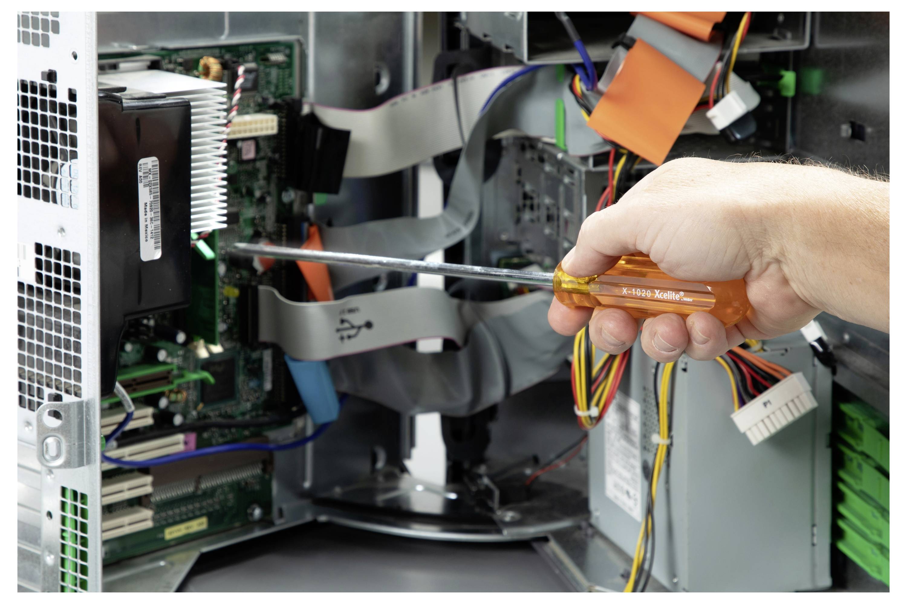 Hand mit einem Schraubenzieher in einem offenen Desktop-Computer, arbeitet zwischen internen Kabeln und Komponenten.