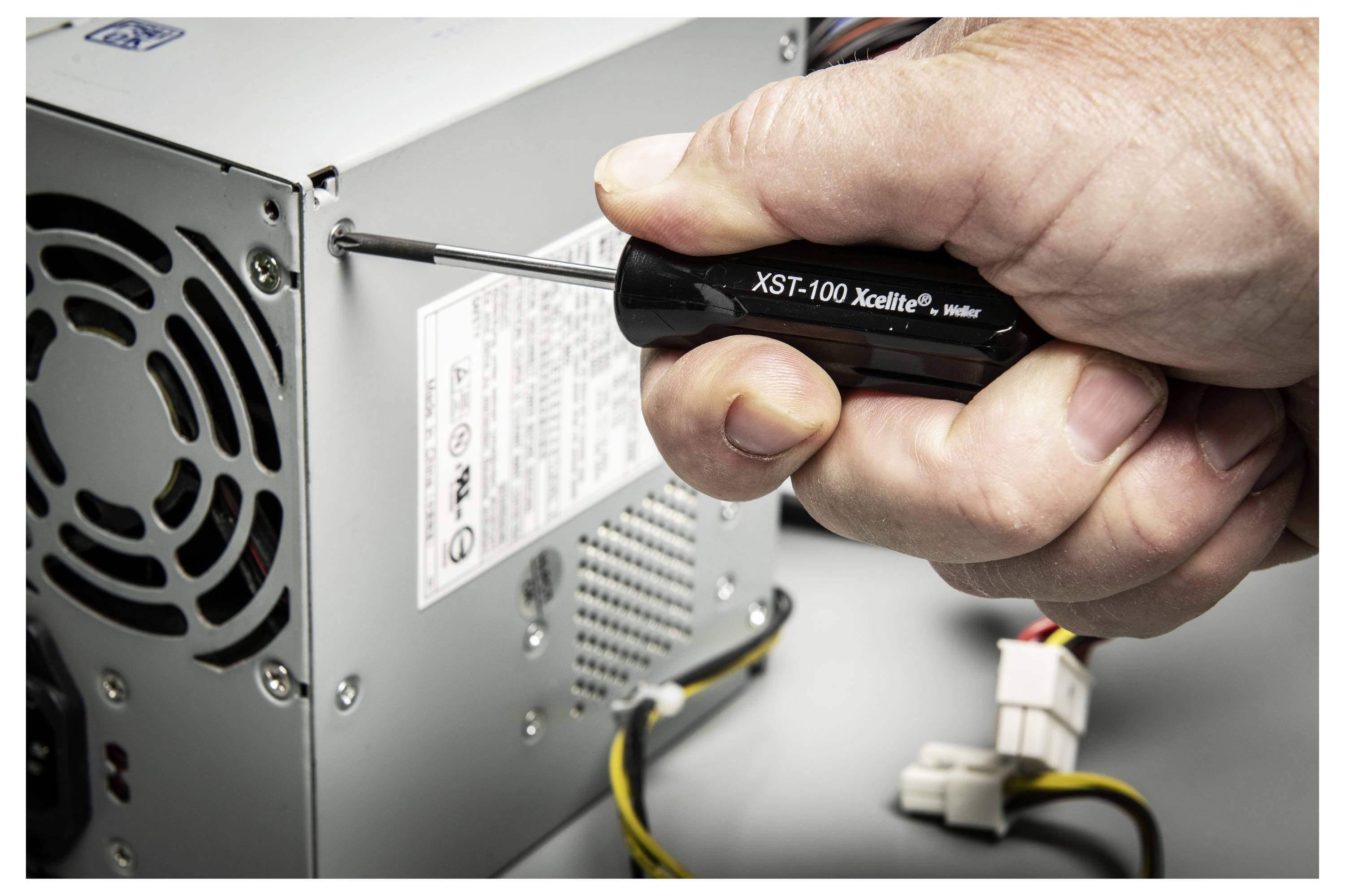 Hand, die einen Schraubendreher verwendet, um eine Schraube auf der Rückseite eines Desktop-Computers oder einer Stromversorgungseinheit zu lockern.