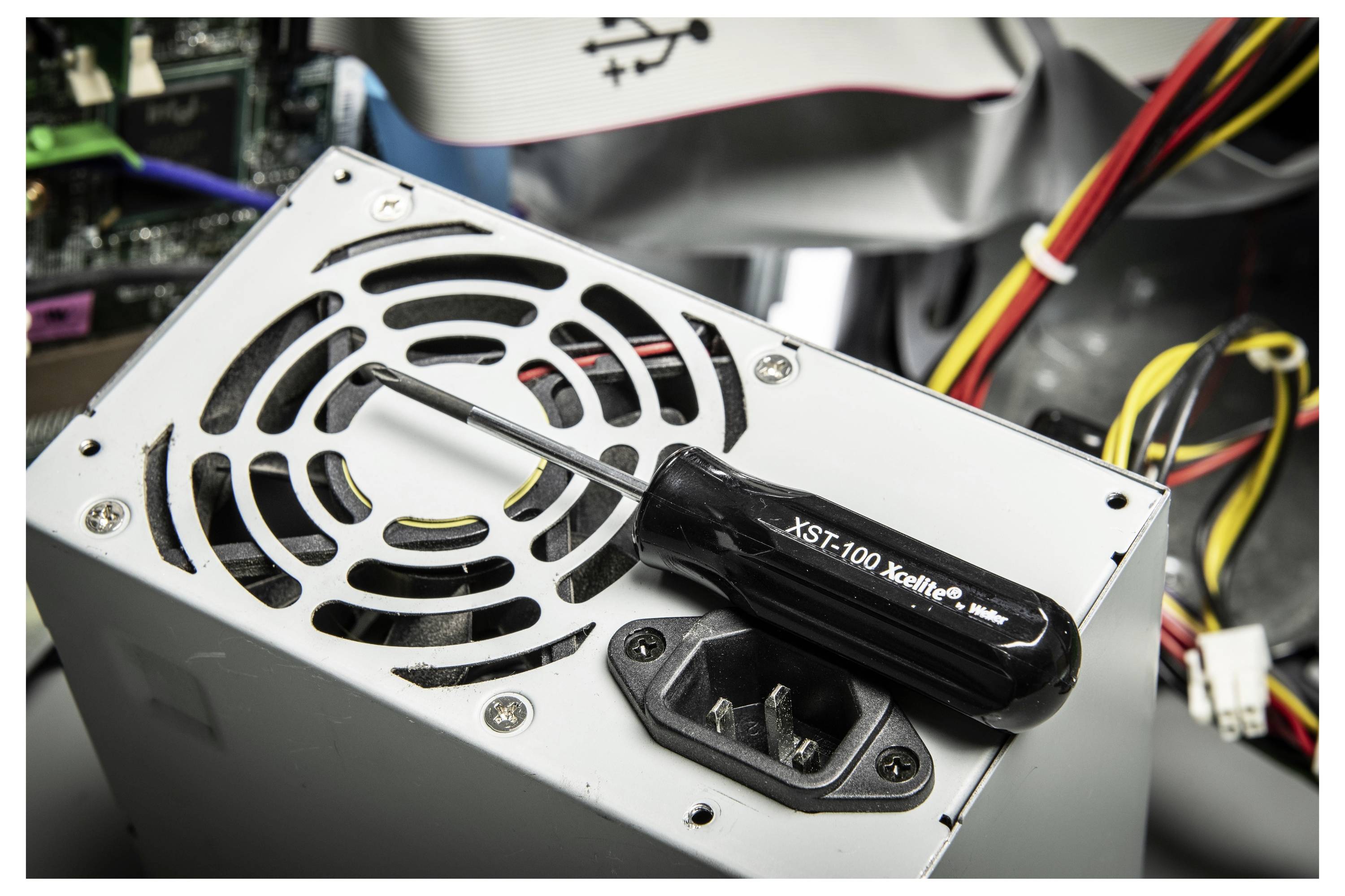 Nahaufnahme eines Computer-Stromversorgungsgeräts mit Kühlventilator, AC-Stromeingang und Kabeln in einem Desktop-Gehäuse.