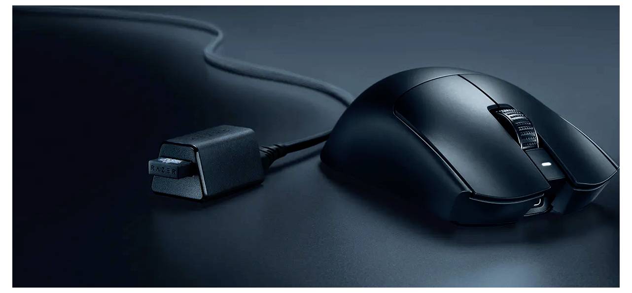 Schwarze schnurgebundene Computermaus auf einer dunklen Oberfläche, mit sichtbarem USB-Kabel und Stecker.