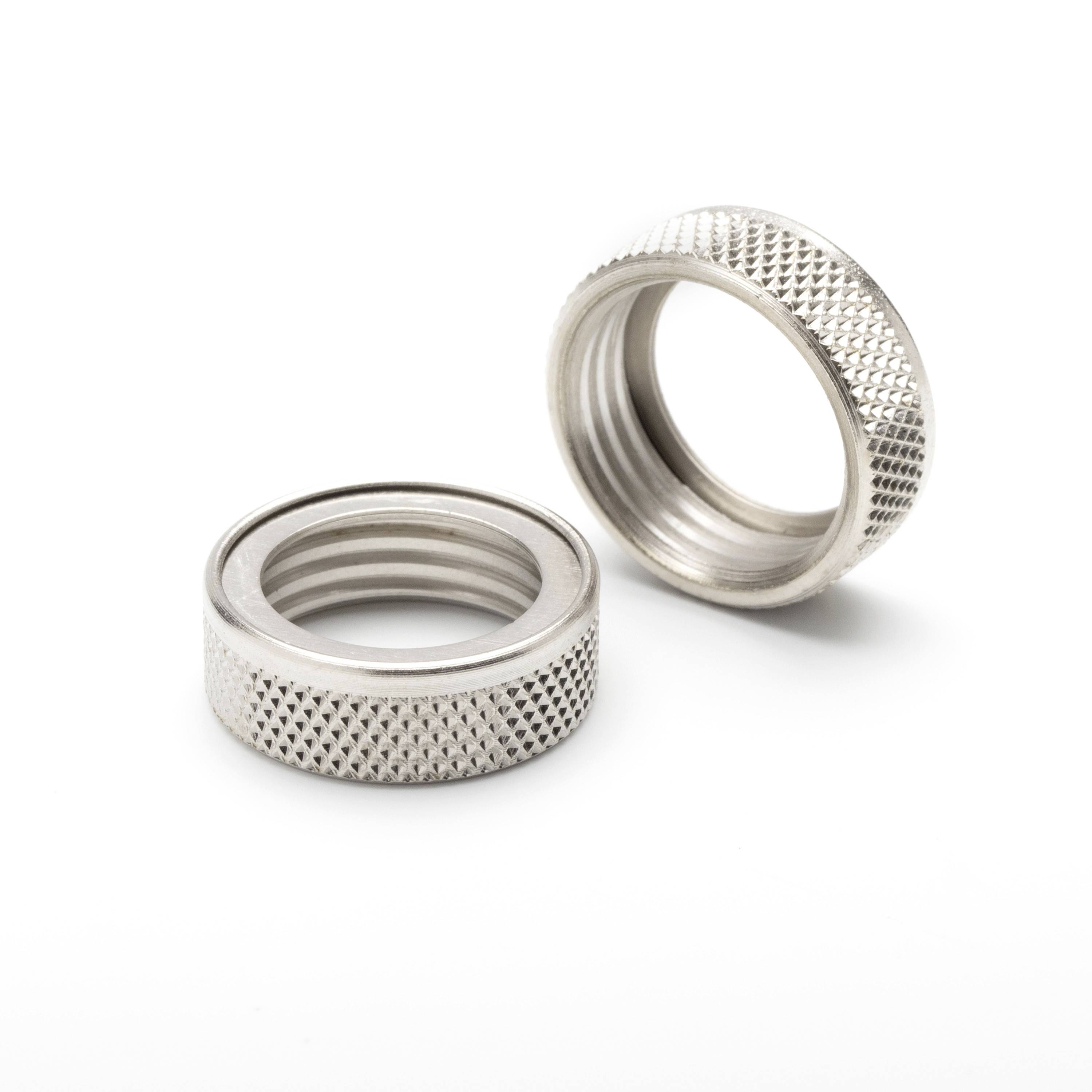 Two metal knurled threaded rings, one lying flat and one standing upright on a white background.