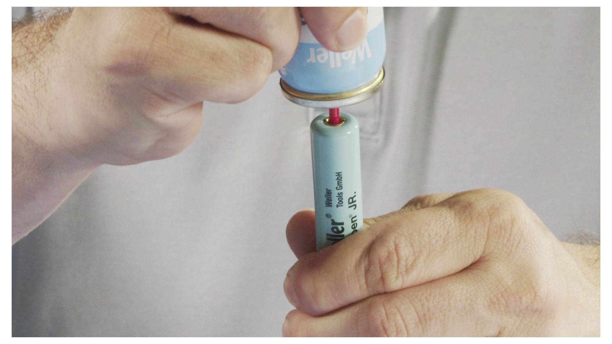 Hands use a small canister to refill a light-blue Welter butane lighter through its bottom valve.