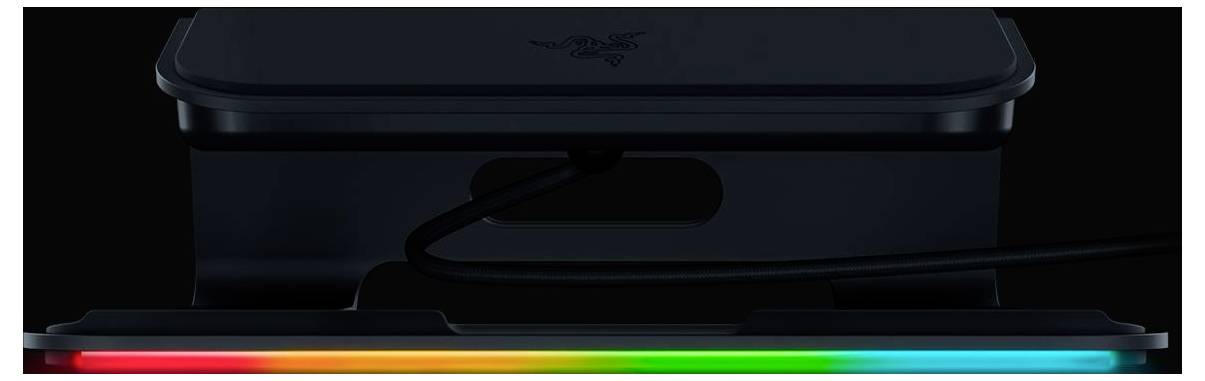 Nahaufnahme eines schwarzen elektronischen Geräts mit einem leuchtenden RGB-Lichtstreifen entlang der unteren Kante und einem Kabel, das in die Seite eingesteckt ist.