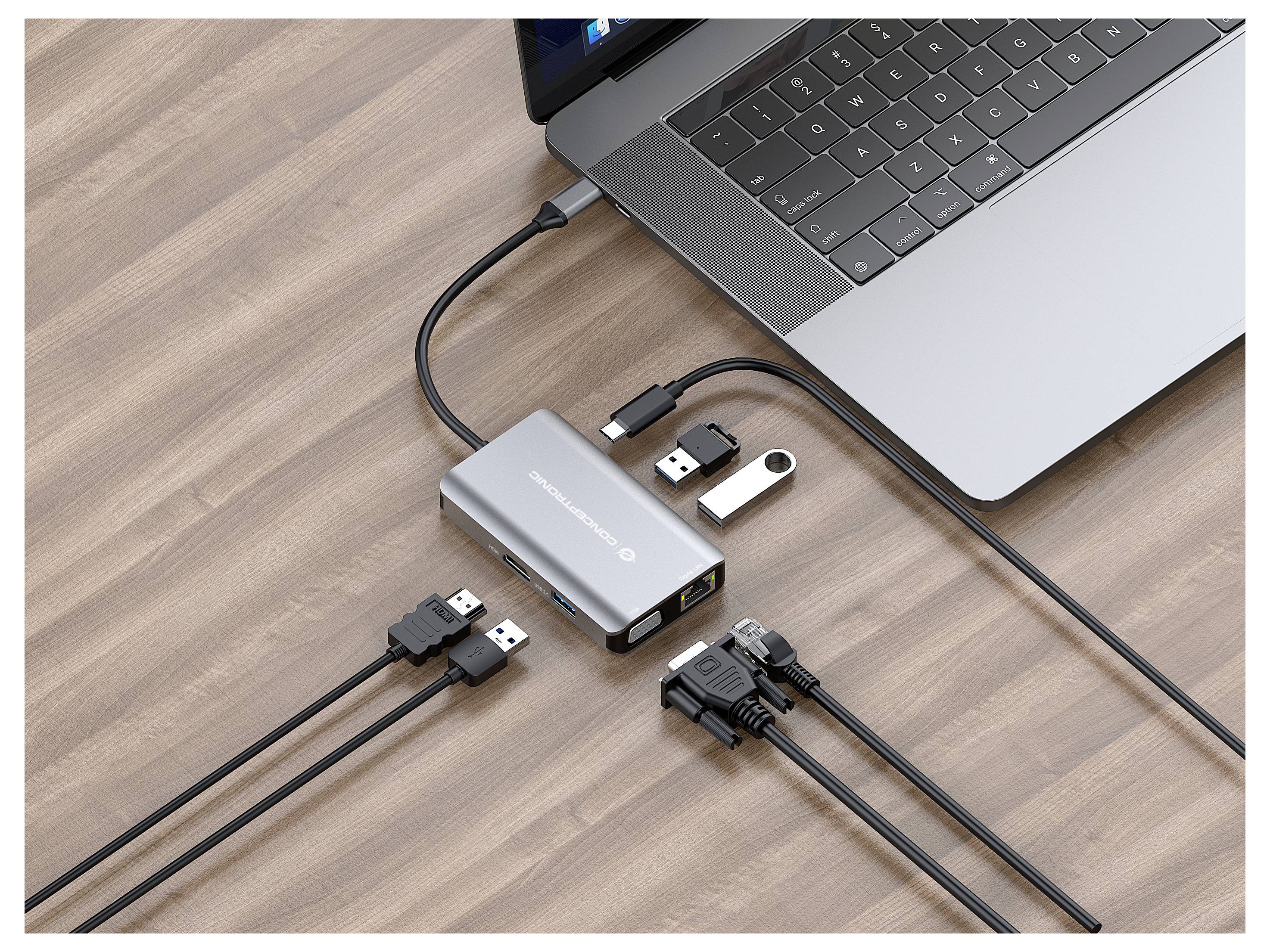 Laptop, das an einen USB-Hub/Dockingstation auf einem Schreibtisch angeschlossen ist, mit mehreren USB-Kabeln und einem USB-Stick, die eingesteckt sind.
