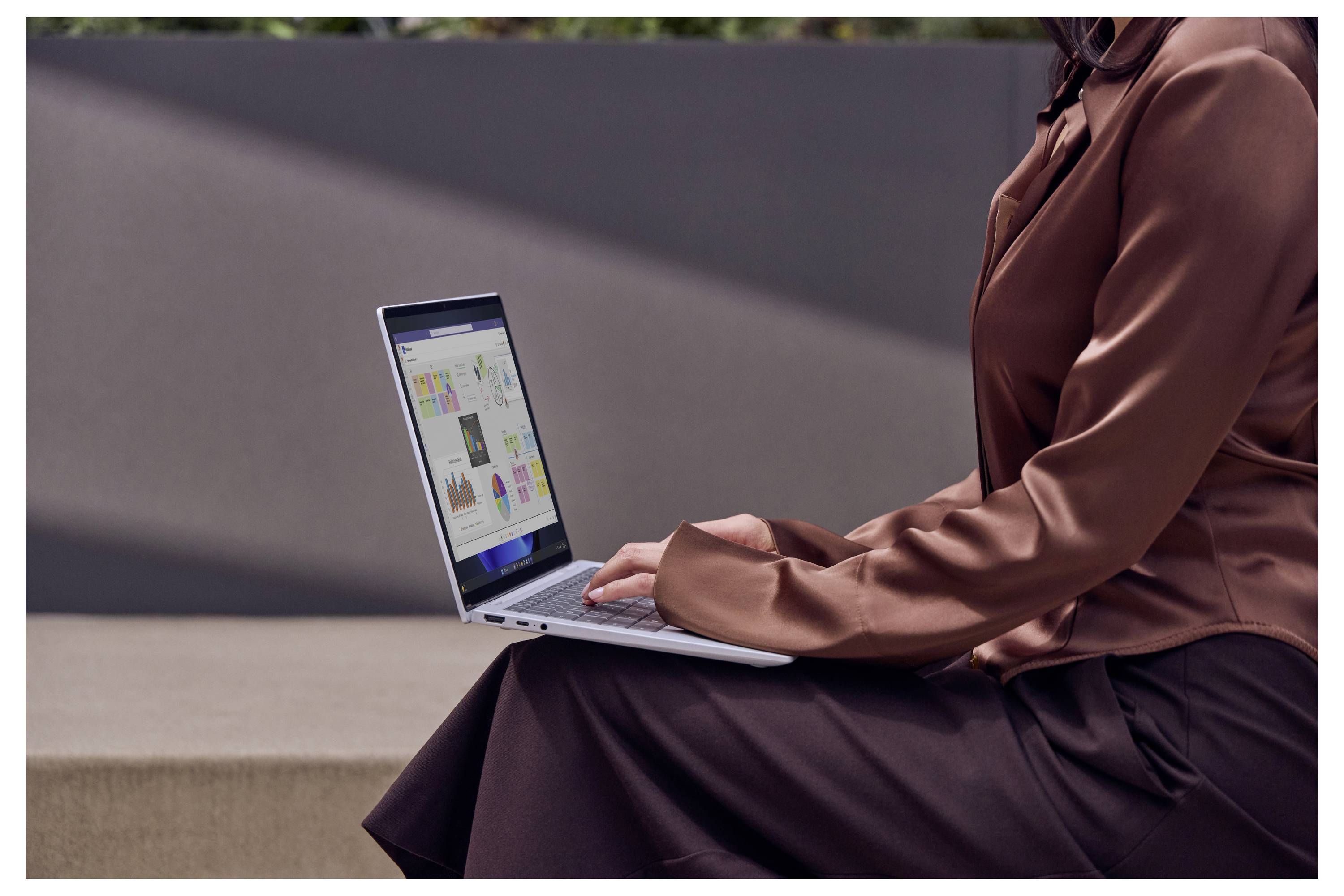 Person sitzt mit einem Laptop auf dem Schoß, tippt und schaut sich farbenfrohe Diagramme oder Analysen auf dem Bildschirm an.