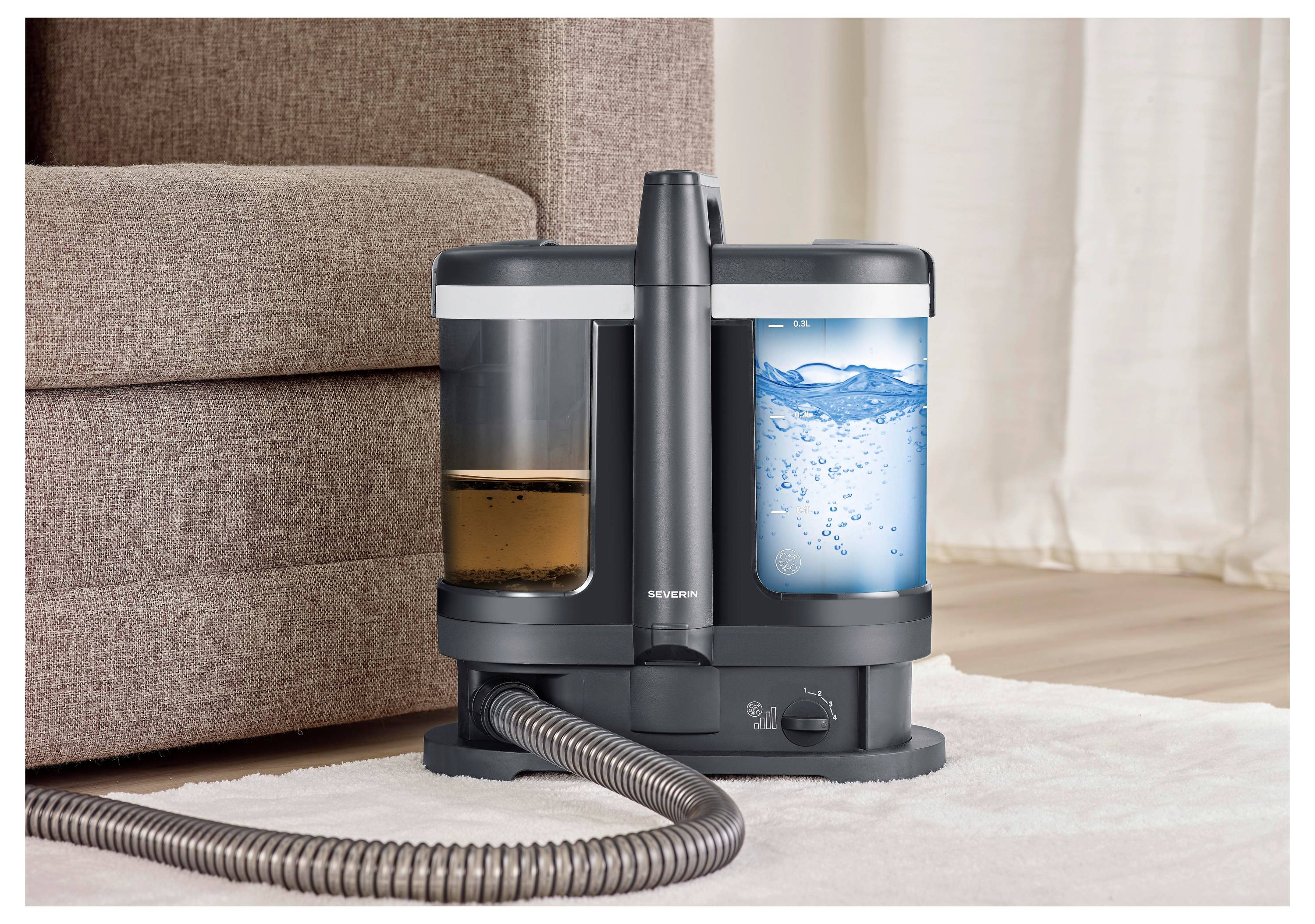 Schnurloses Wasser-Staubsauger-Gerät mit zwei Tanks auf einem Teppich neben einem Sofa, wobei der eine Tank verschmutztes Wasser und der andere sauberes Wasser zeigt.