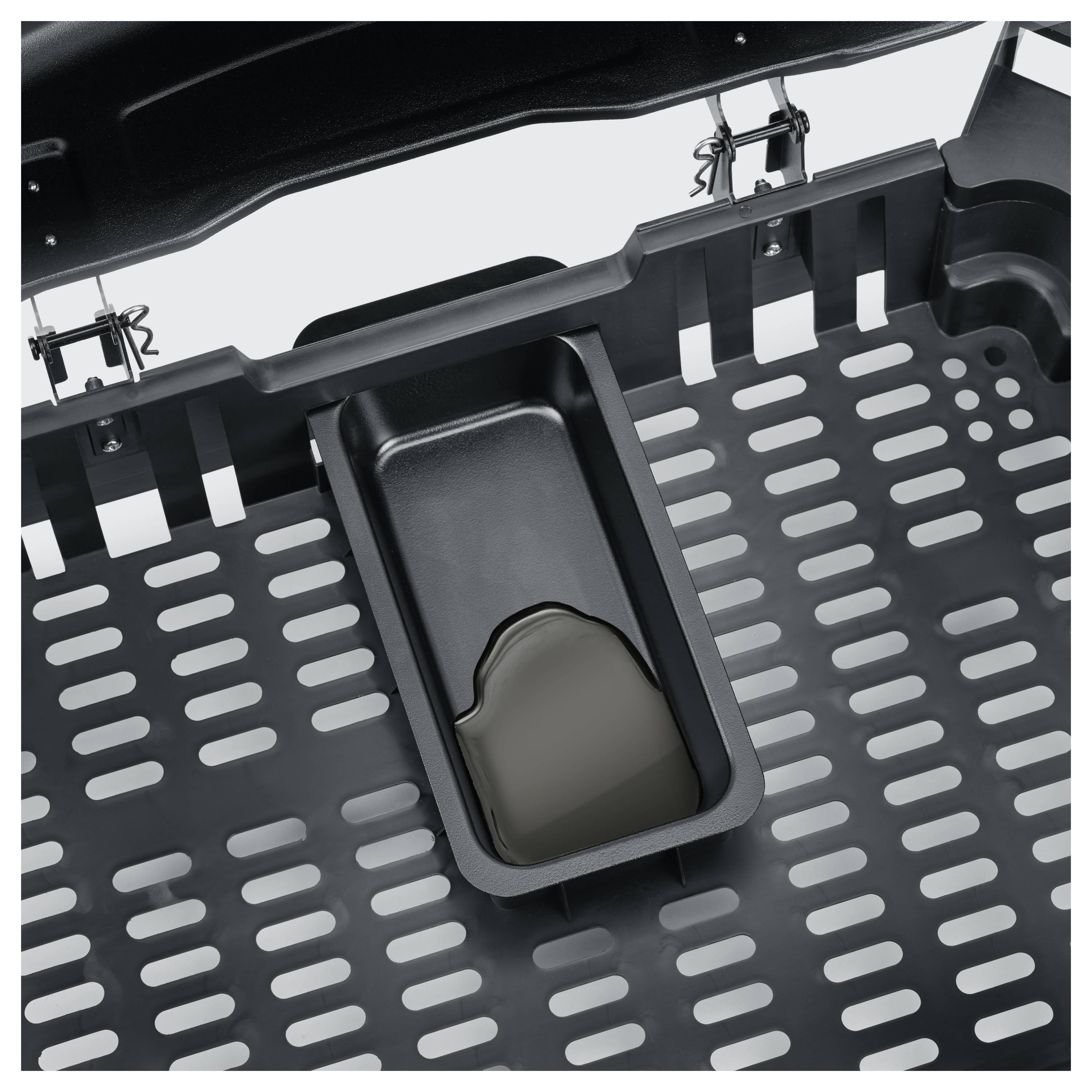 Nahaufnahme eines schwarzen Metallgrills oder Tabletts mit perforierten Schlitzen und einer zentralen rechteckigen Auffangwanne, die Flüssigkeit enthält.