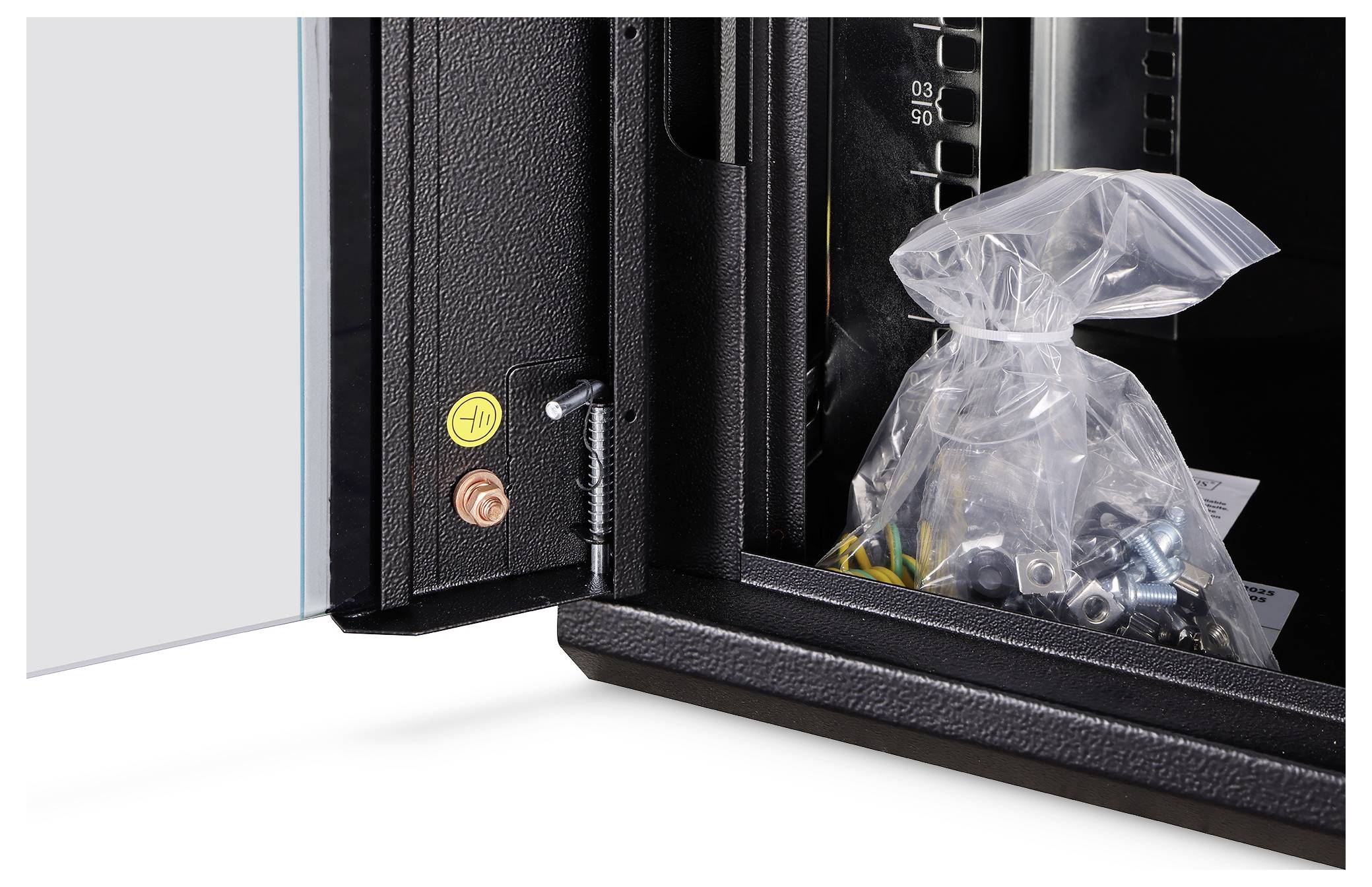 Offener schwarzer Metallschrank oder Safe mit einer Plastiktüte mit Schrauben und Bolzen darin, plus gelbe und orange Steuerknöpfe auf dem Türrahmen.
