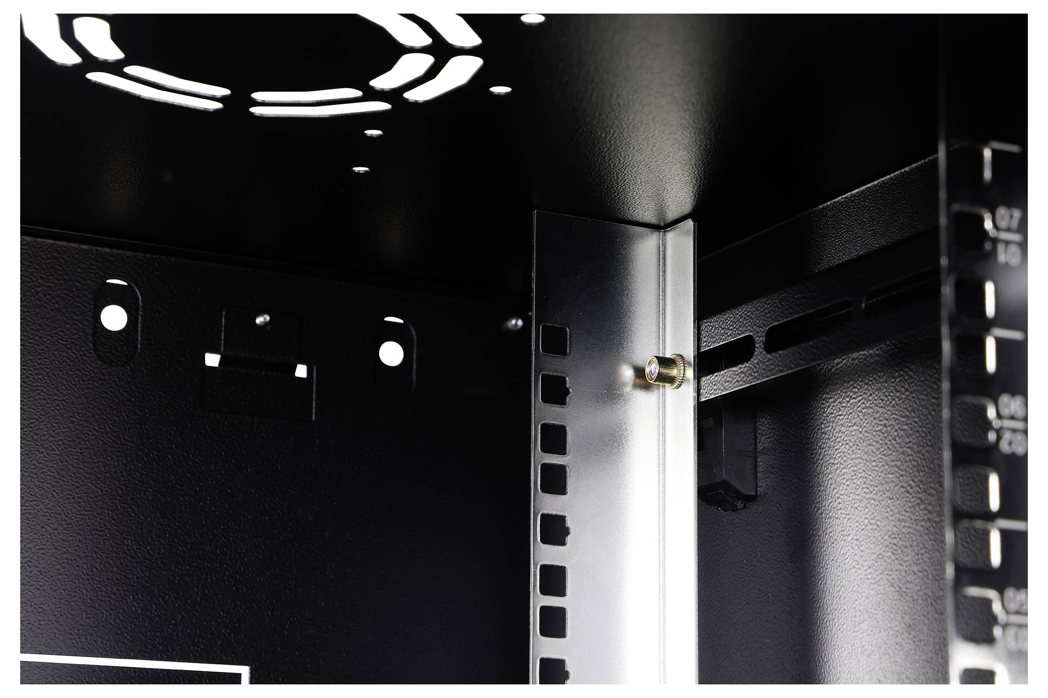 Nahaufnahme des Inneren eines schwarzen Computergehäuses, die eine Metallmontageklammer, Kabelschlitze und einen Gehäuselüfter oben zeigt.