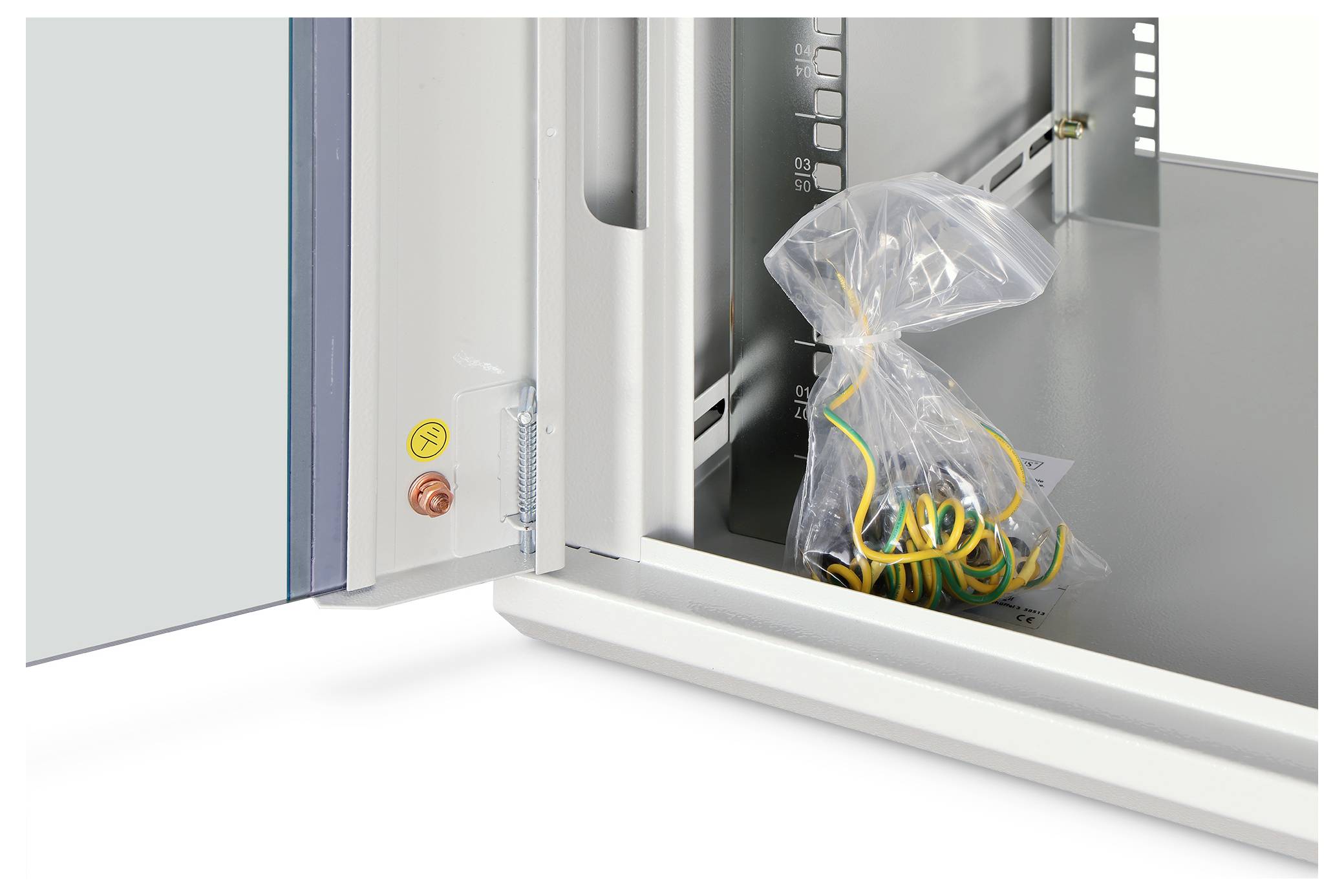 Geöffneter elektrischer Schaltschrank mit einer Plastiktüte gelber und grüner Drähte im Inneren, in der Nähe eines angebrachten Stromschalters und rot/gelber Bedienungstasten.