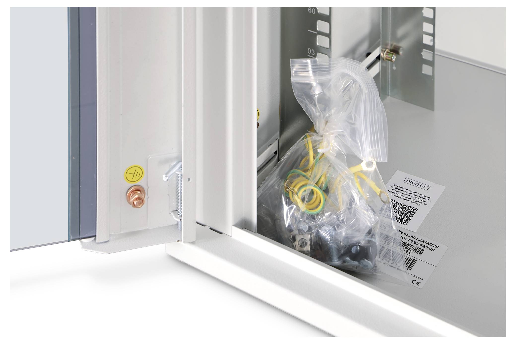 Plastiktüte mit Kabeln und Etiketten in einem Metallschrank für Elektrik oder Servergehäuse mit Glastür.