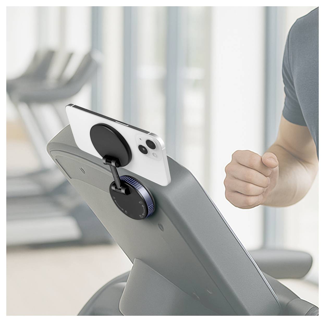 Smartphone auf einem Trainingsgerätebildschirm neben der geballten Faust einer Person in einem Fitnessstudio montiert.