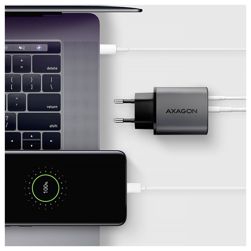 Ansicht von oben auf einen Laptop, der über einen AXAGON USB-C-Wandadapter und eine angeschlossene Powerbank aufgeladen wird, mit Kabeln, die in beide Geräte eingesteckt sind.
