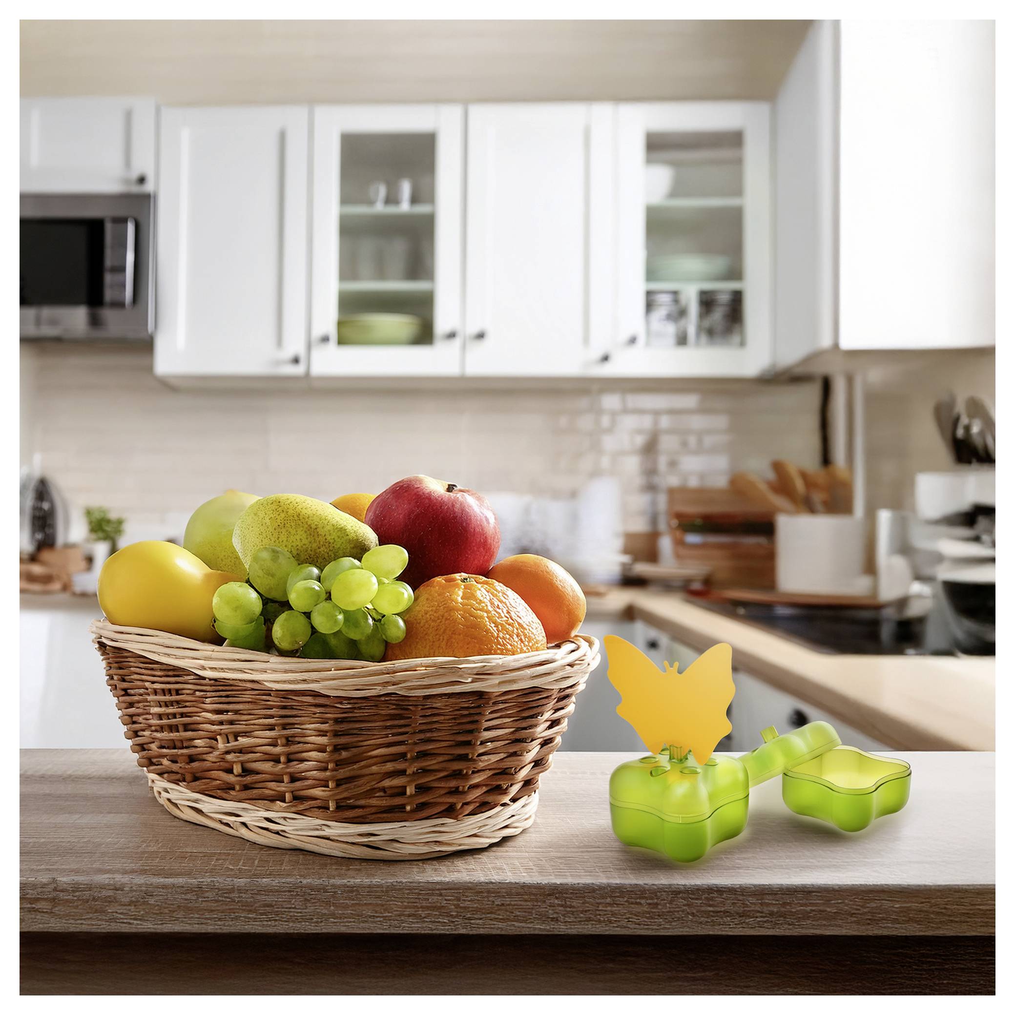 Korbgeflecht mit assortiertem Obst auf einer Küchentheke neben grünen schmetterlingsförmigen Ausstechern.