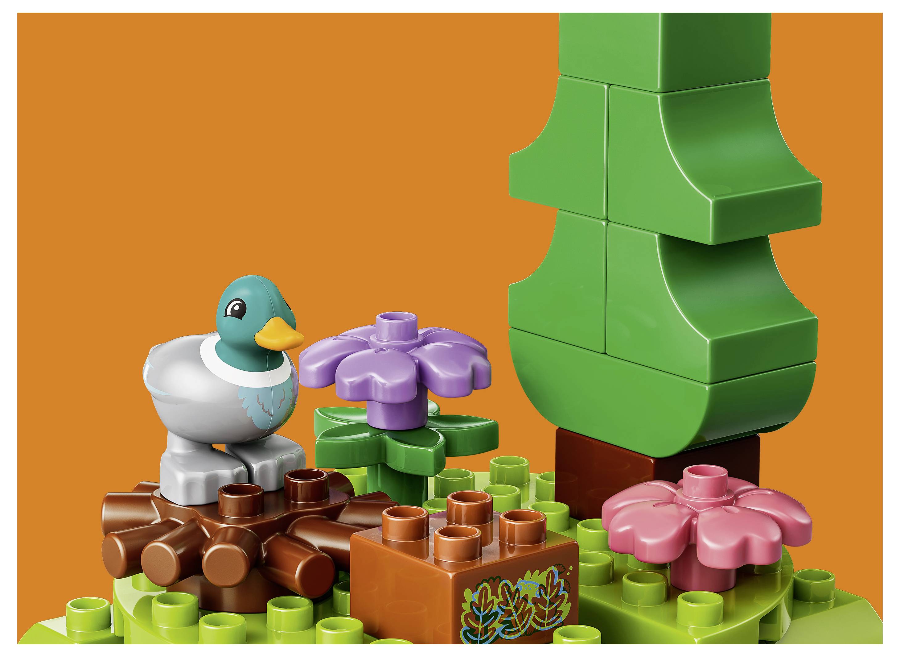 Bunte LEGO-ähnliche Szene mit einer Ente, Blumen und einem großen grünen Baum auf orangefarbenem Hintergrund.