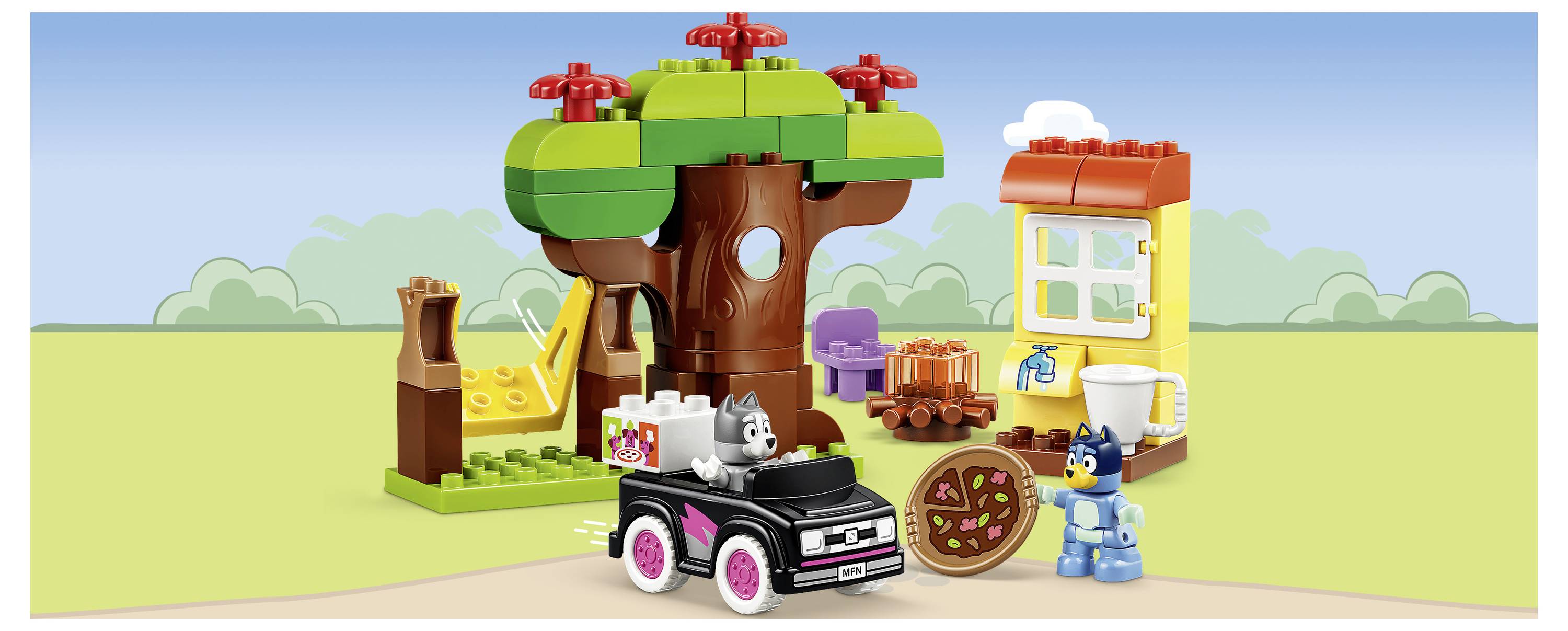 LEGO-ähnliche Szene eines Baumhaus-Marktes mit einem schwarzen Auto, einer grauen Katze, einer blauen Minifigur und einem Obstkarren unter einem großen Baum.