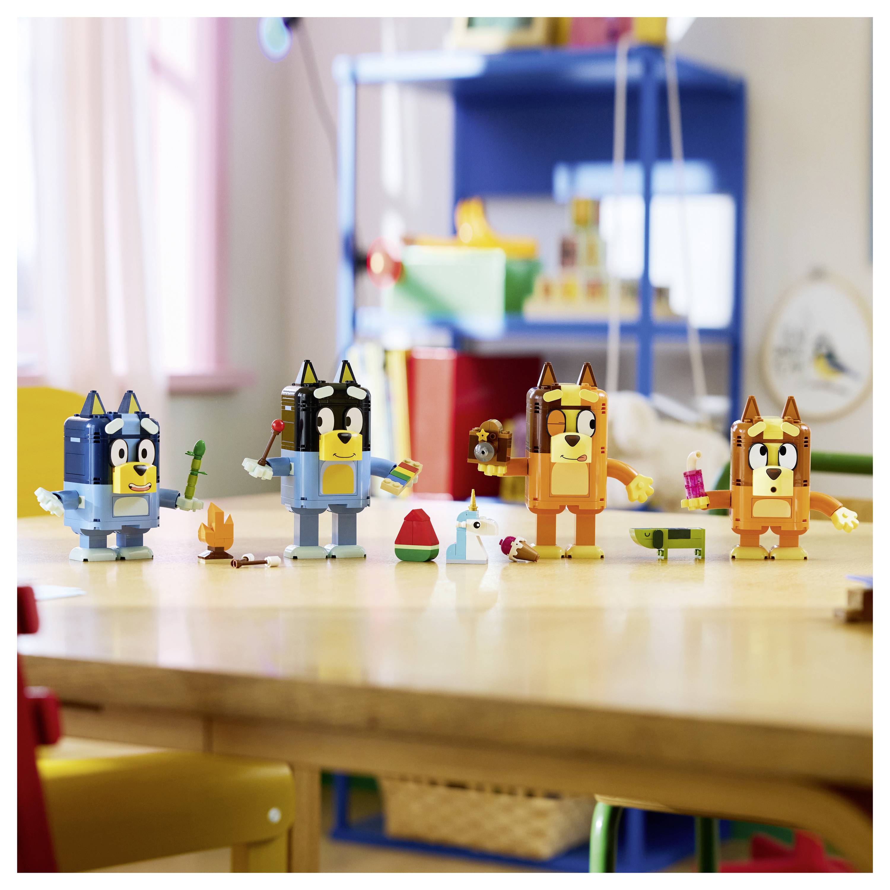 Vier Spielzeughundfiguren stehen auf einem Klassentisch mit kleinen Bastelteilen, die um sie herum verstreut sind.
