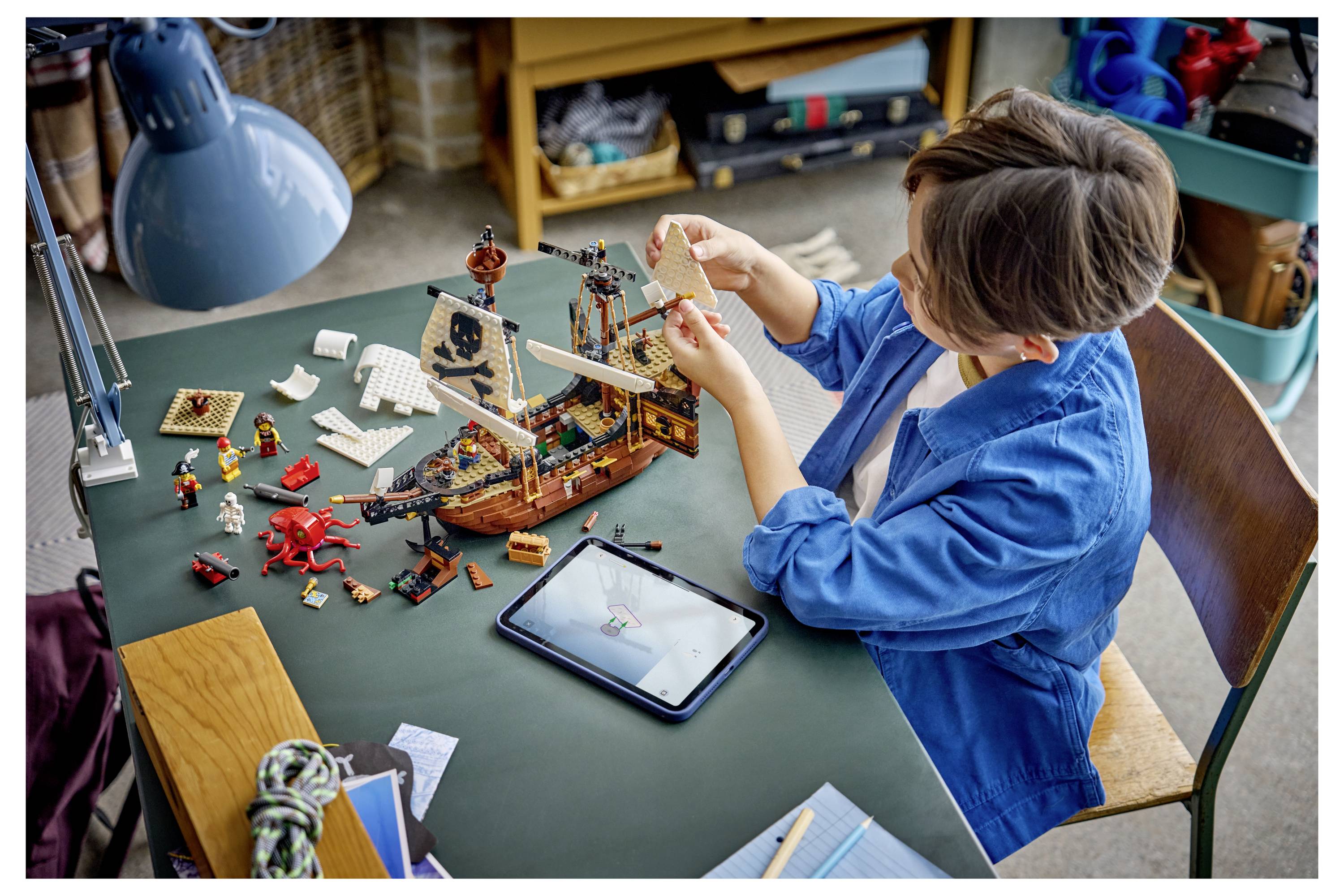 Ein roter Spielzeugroboter steht auf einem niedrigen Holztisch, mit zwei kleinen Spielzeugfiguren und einem Fahrzeug daneben in einem Kinderzimmer.