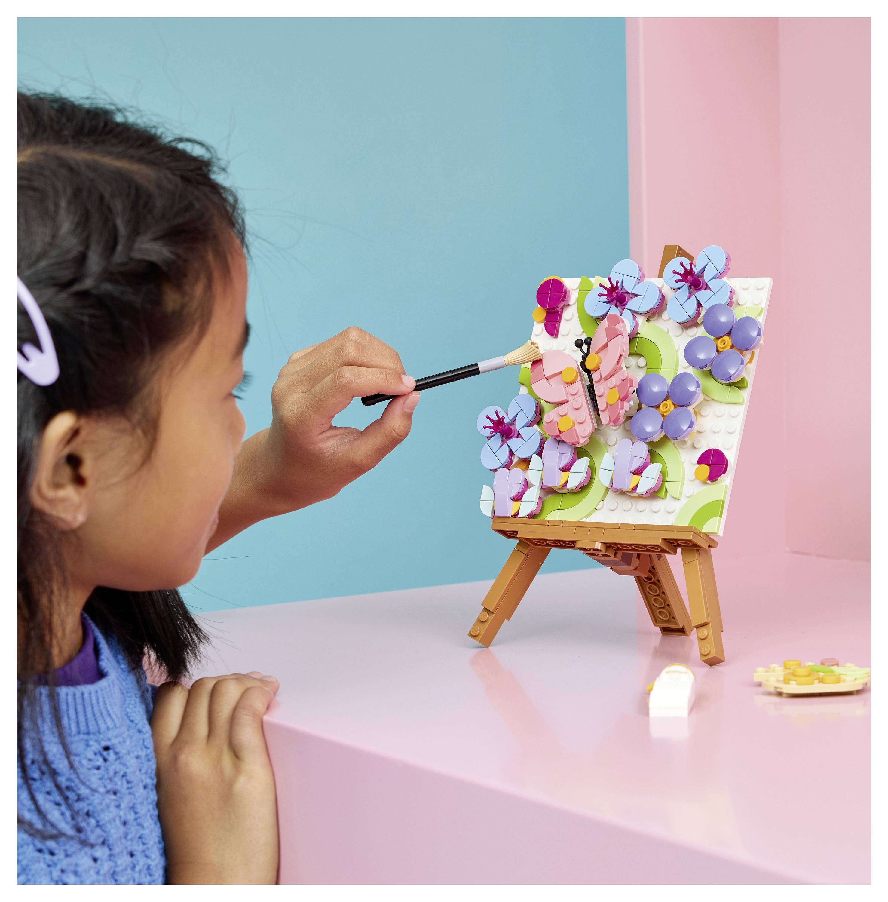 Zwei Kinder lächeln, während sie bunte blumenförmige Spielzeugmodelle an einem Tisch im Innenraum zusammenbauen.