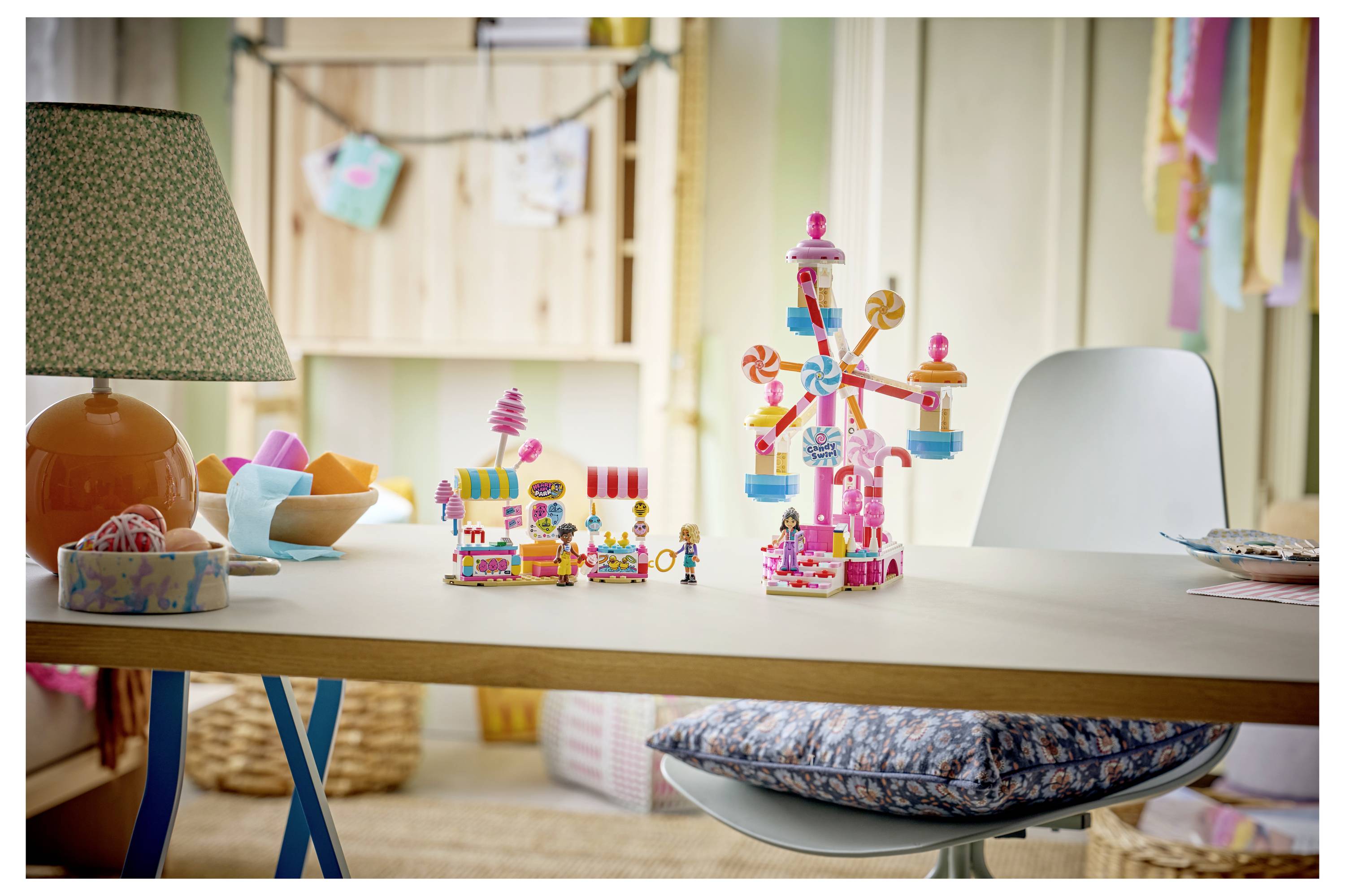 Eine Tischplatte-Ausstellung mit bunten Spielzeugbausteinen, einschließlich einer hohen Riesenrad-Struktur und kleinen shopähnlichen Bauten in einem Kinderzimmer.