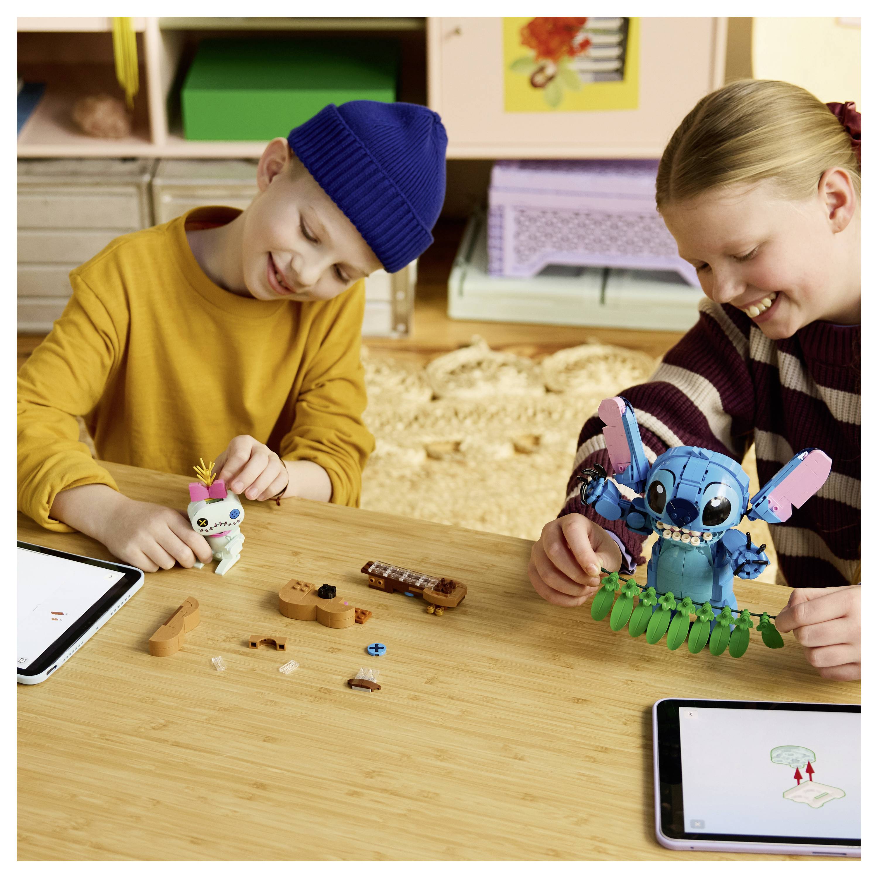 Zwei Kinder, die an einem Tisch kleine Spielzeugroboter bauen, mit Tablets in der Nähe, die Anweisungen anzeigen.