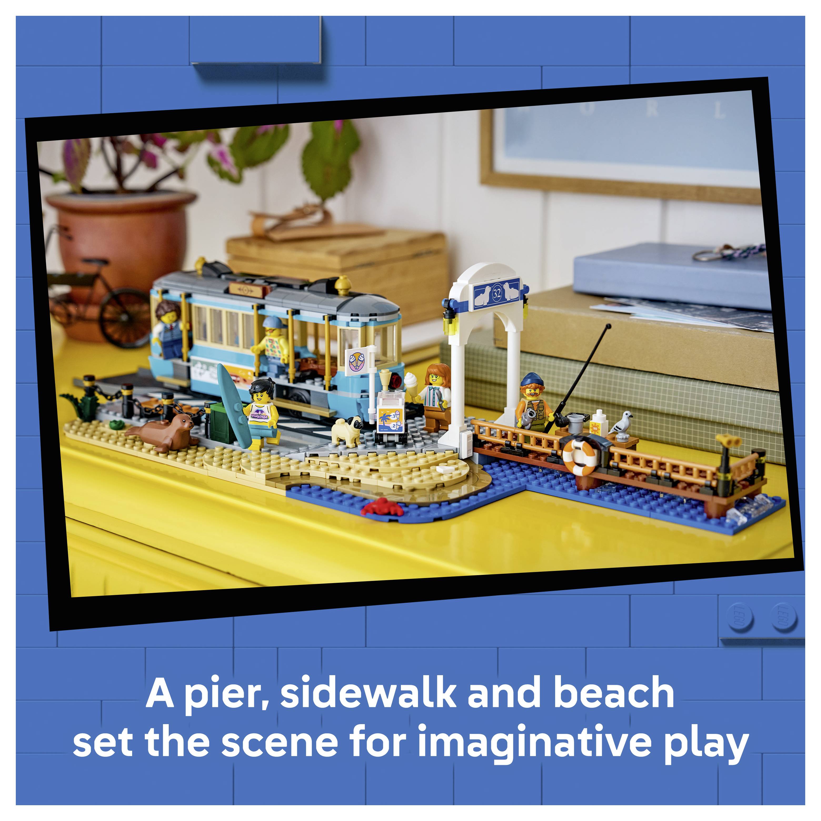 LEGO-Strandspielset mit Anlegesteg, Gehweg, Strand, Straßenbahn, Dock und Minifiguren; die Bildunterschrift lautet „Ein Anlegesteg, Gehweg und Strand bilden die Kulisse für fantasievolles Spielen
