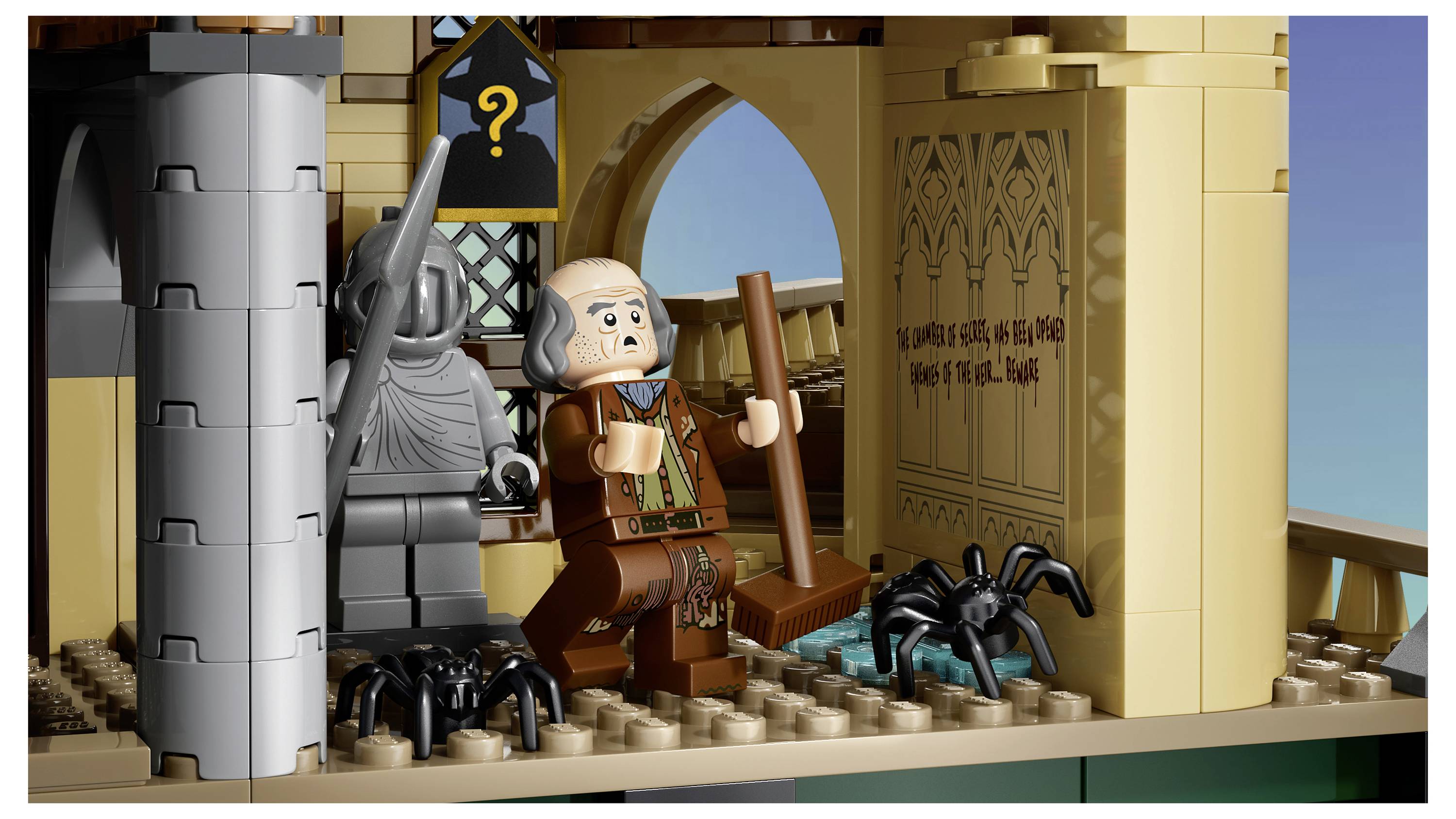 LEGO-Szene eines älteren Mannes mit einem Stab in einer Steinkammer, mit Spinnen auf dem Boden, einer vermummten Figur mit einem Fragezeichen und einer Türöffnung nach draußen.