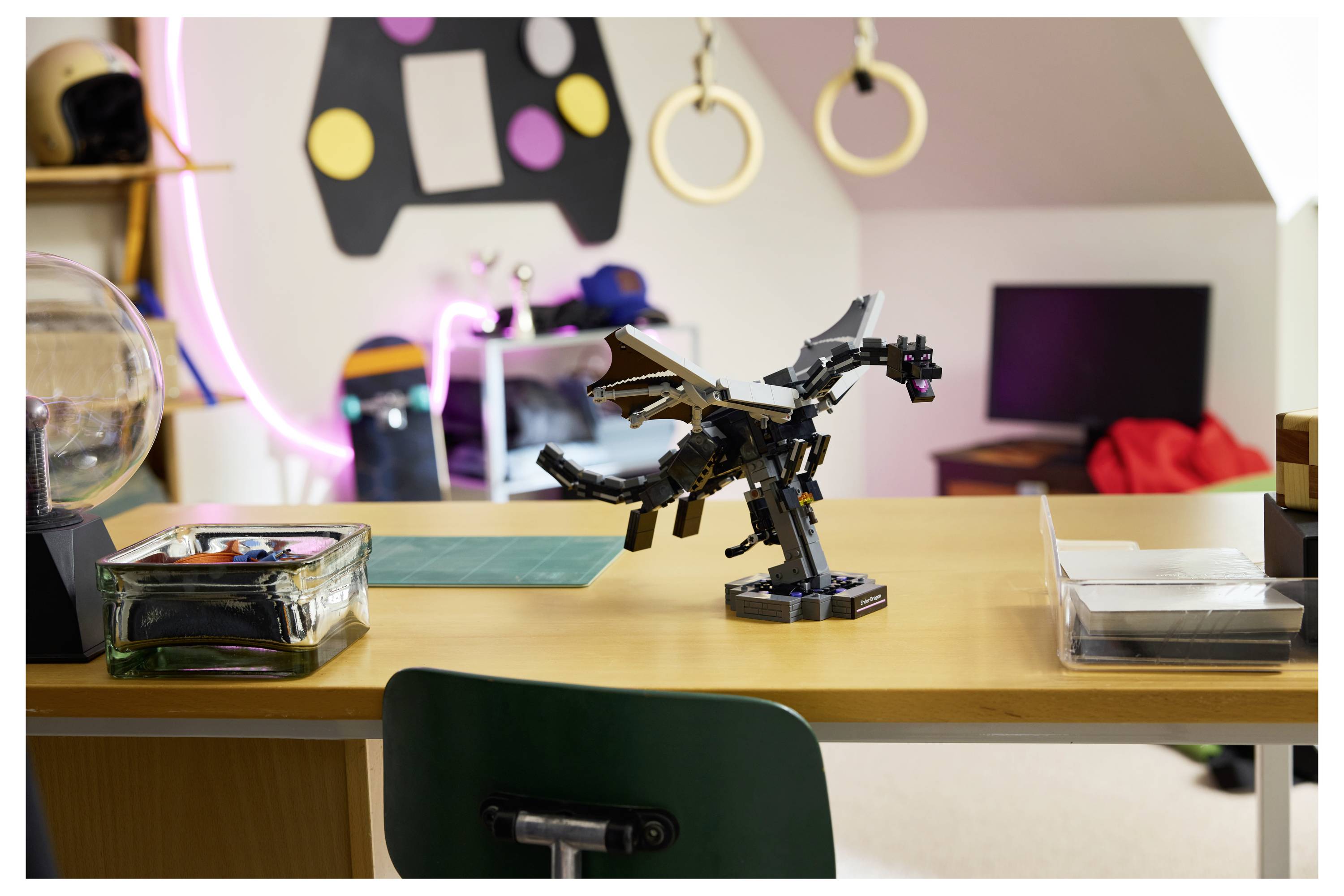 Ein schwarzes LEGO-Drachenmodell steht auf einem Holzschreibtisch in einem farbenfrohen Bastelzimmer, mit Aufbewahrungsboxen und einem Computer im Hintergrund.