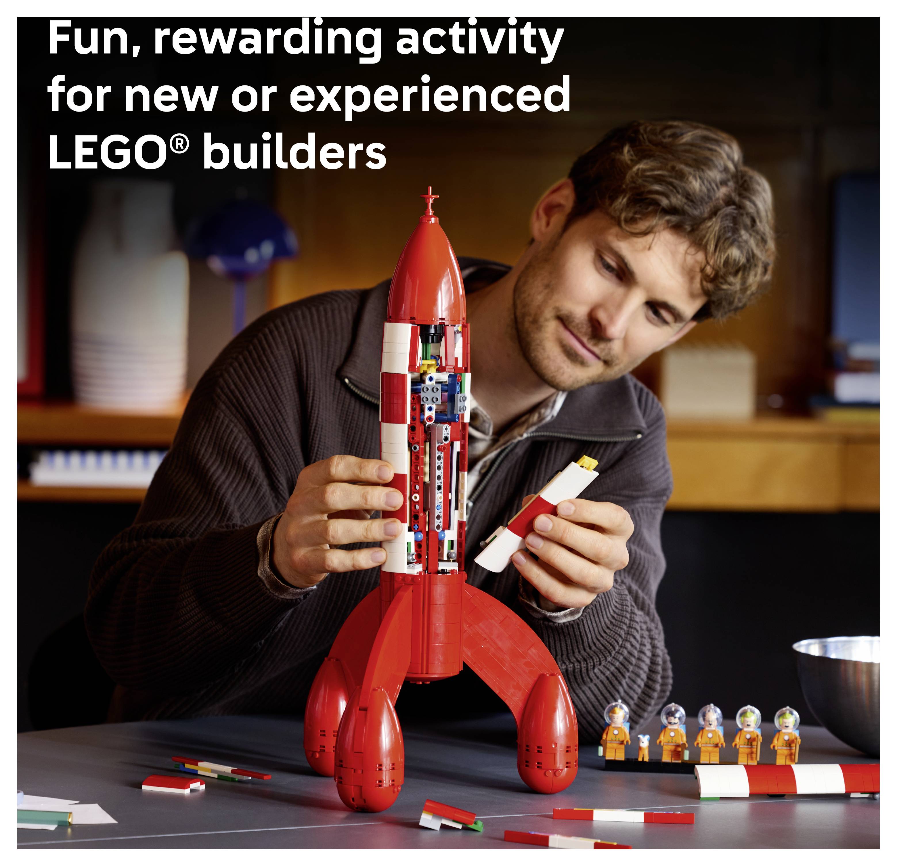 Mann montiert ein rotes LEGO-Raketenmodell, mit Text, der besagt „Unterhaltsame, lohnende Aktivität für neue oder erfahrene LEGO-Bauer