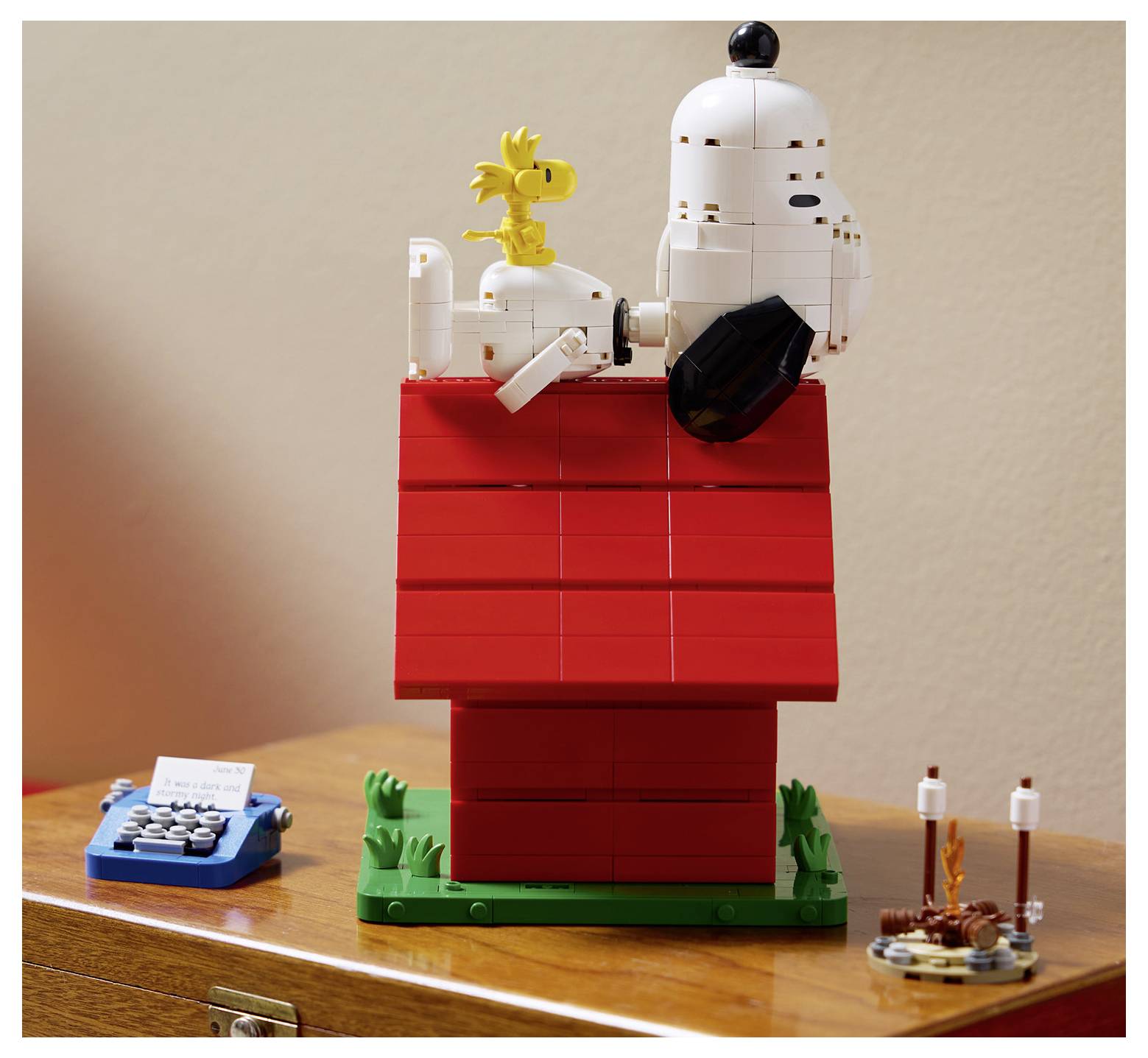 LEGO-Modell von Snoopy auf einem roten Hundehütte mit Woodstock, ausgestellt auf einem Holztisch.