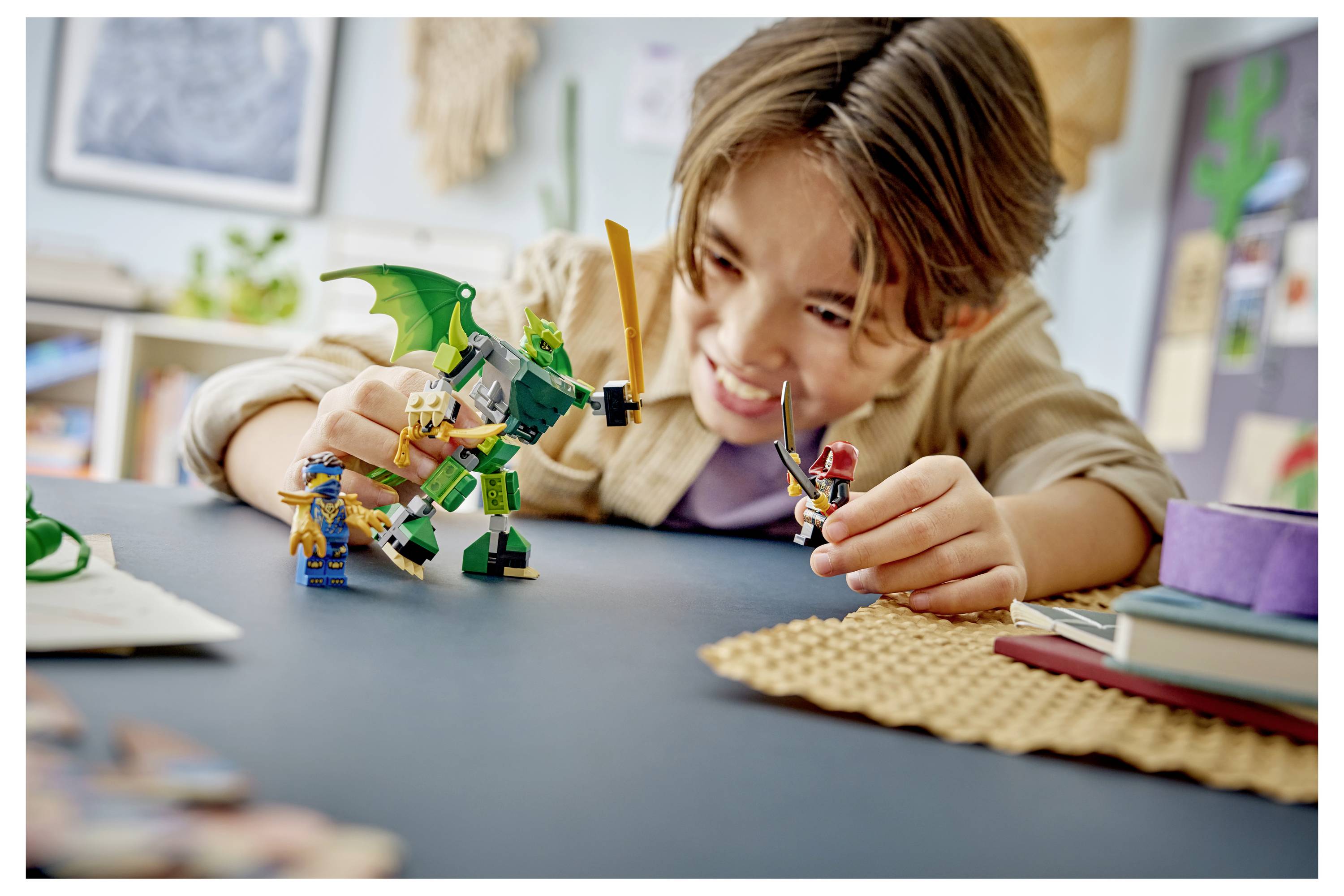 Kind spielt mit LEGO-ähnlichen Drachenspielsachen und Minifiguren auf einem Tisch und lächelt in einem hellen Raum.