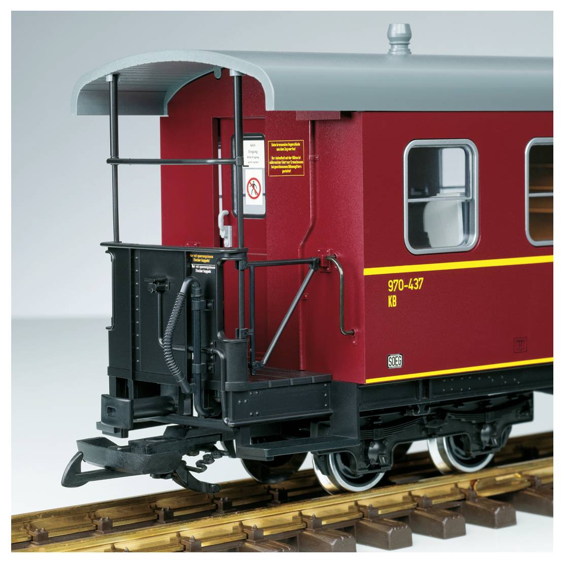 Nahaufnahme eines roten Modell-Eisenbahn-Güterwagens auf Gleisen, die die hintere Plattform, Fenster und die gelbe Identifikationsnummer 97-0-437 zeigt.
