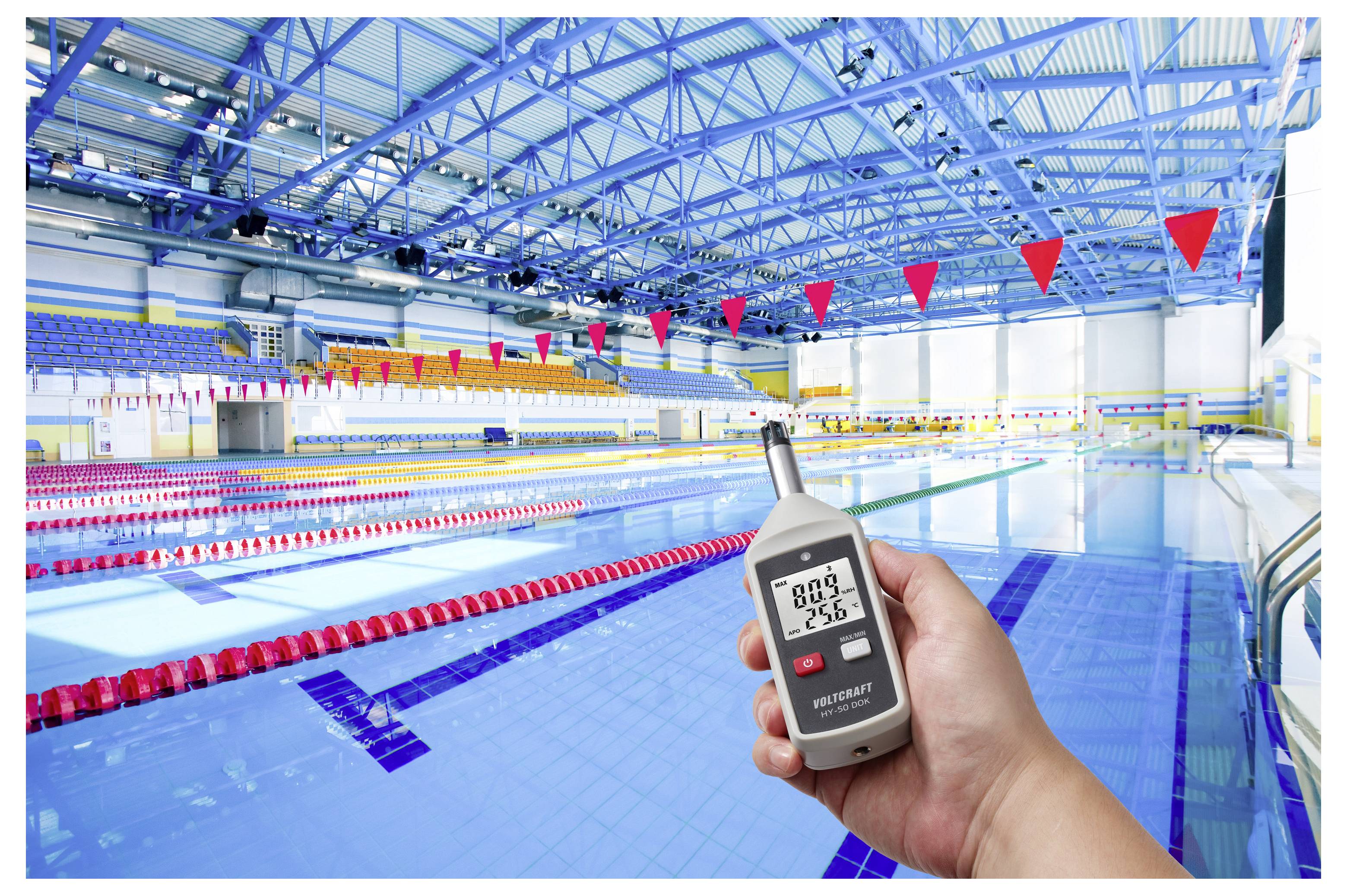 Hand hält ein digitales Schallpegelmessgerät mit einer Anzeige von 68,9 dB und 25,8°C in einem Hallenbad mit Bahnen und roten Wimpeln.