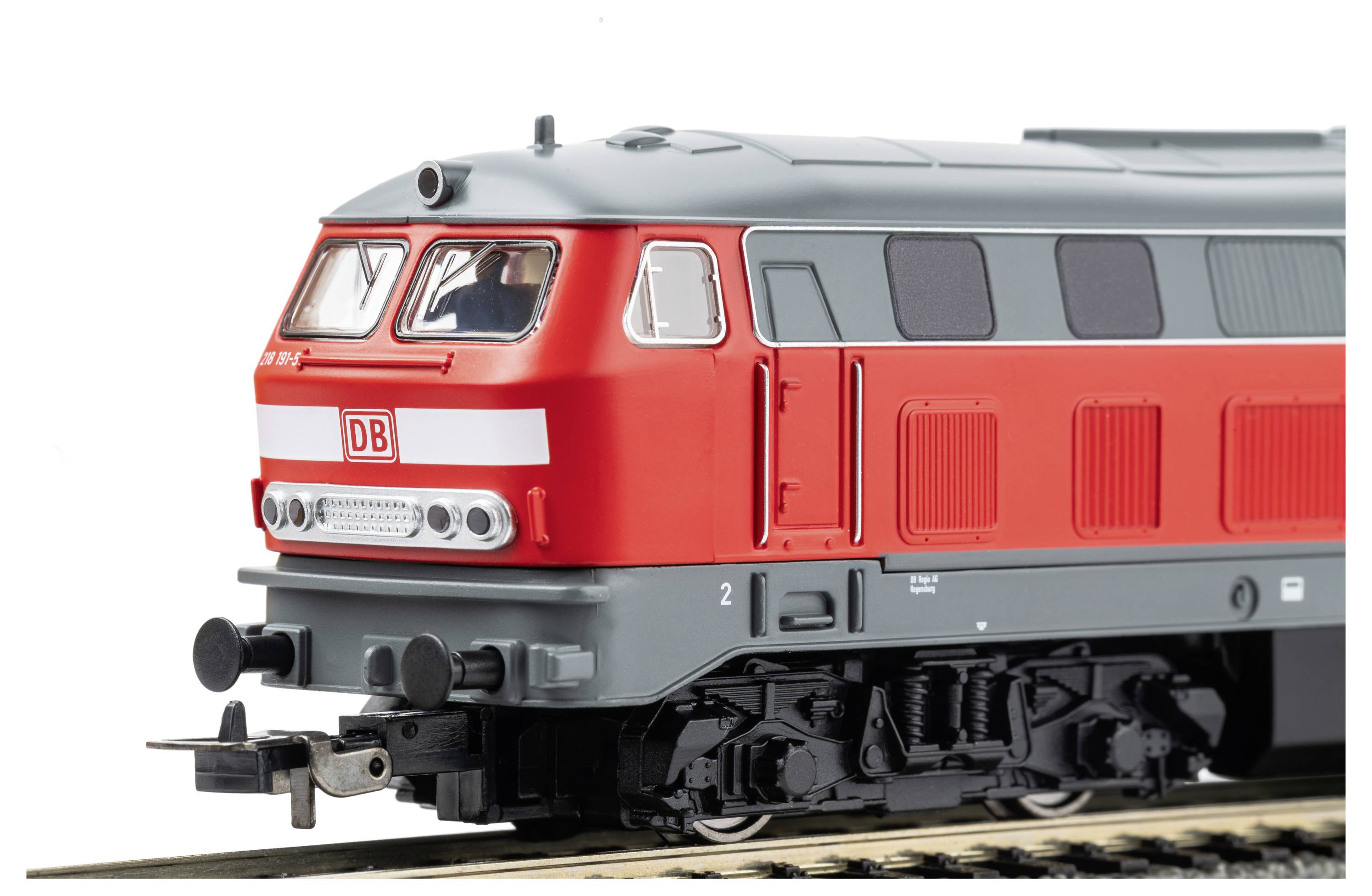 Rote ÖBB-Diesellokomotive in Seitenansicht auf Gleisen, mit weißem ÖBB-Logo und silbernem Dach vor weißem Hintergrund.