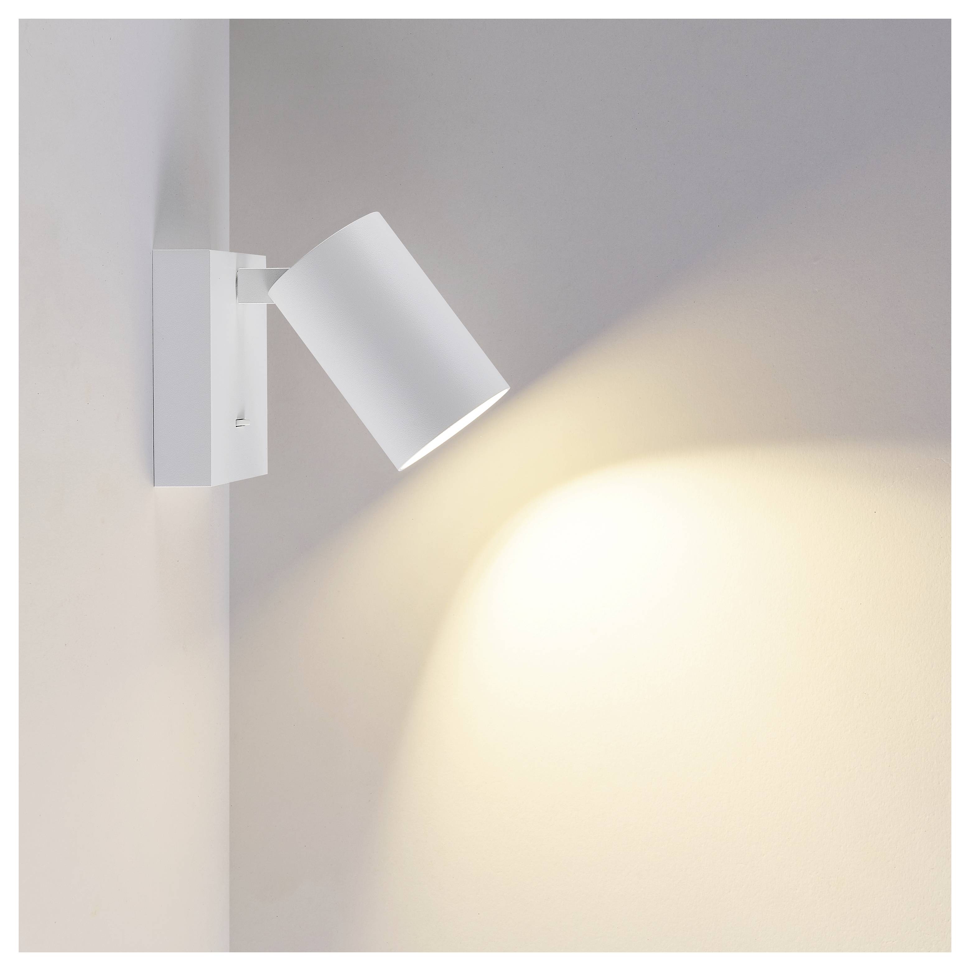 Weißer verstellbarer Wandstrahler, der einen warmen Lichtkegel über eine schlichte Innenwand wirft.