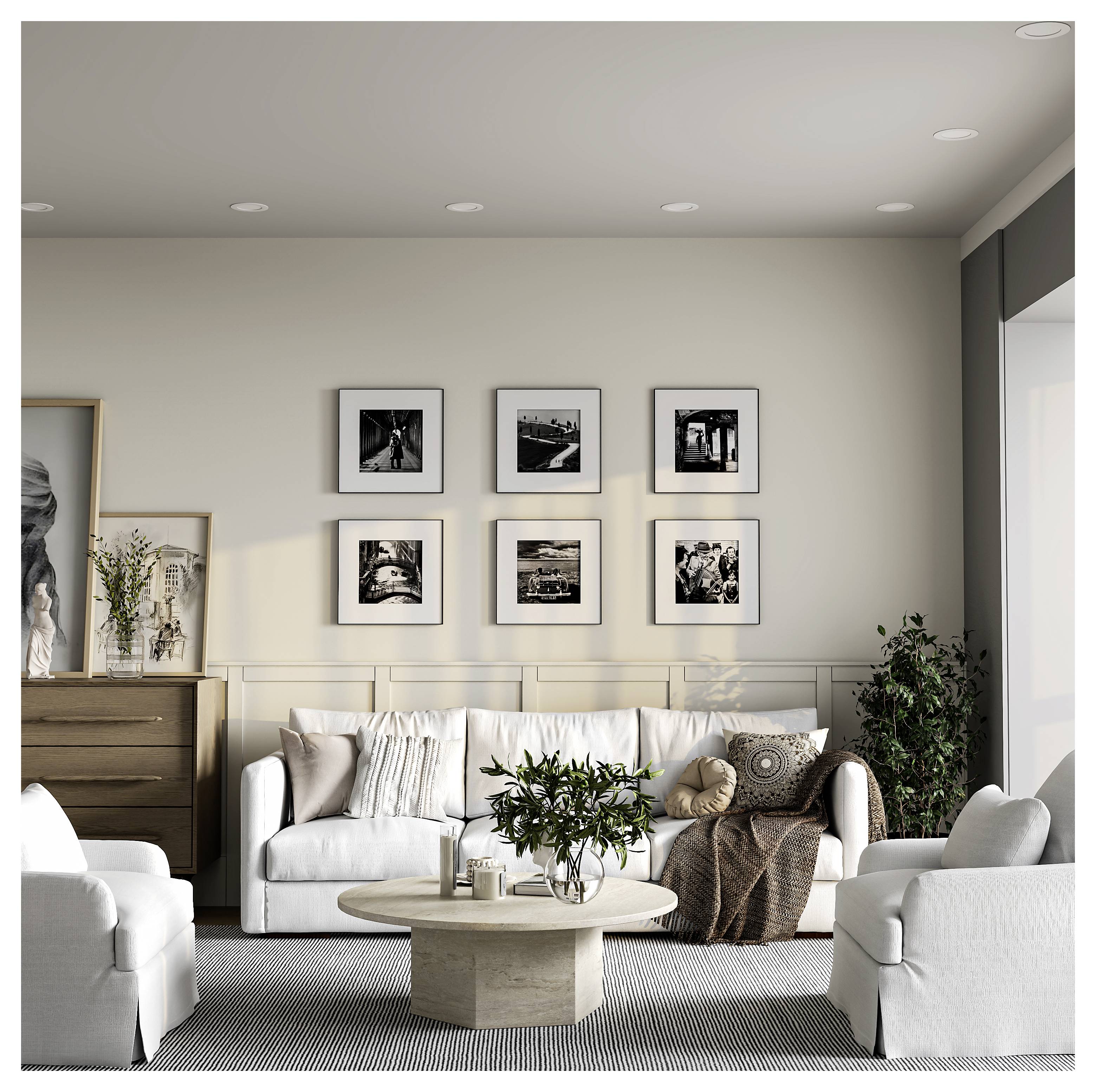 Modernes Wohnzimmer mit weißen Sofas, rundem Couchtisch, Kommode, Topfpflanzen und sechs gerahmten Schwarzweiß-Fotos an der Wand.