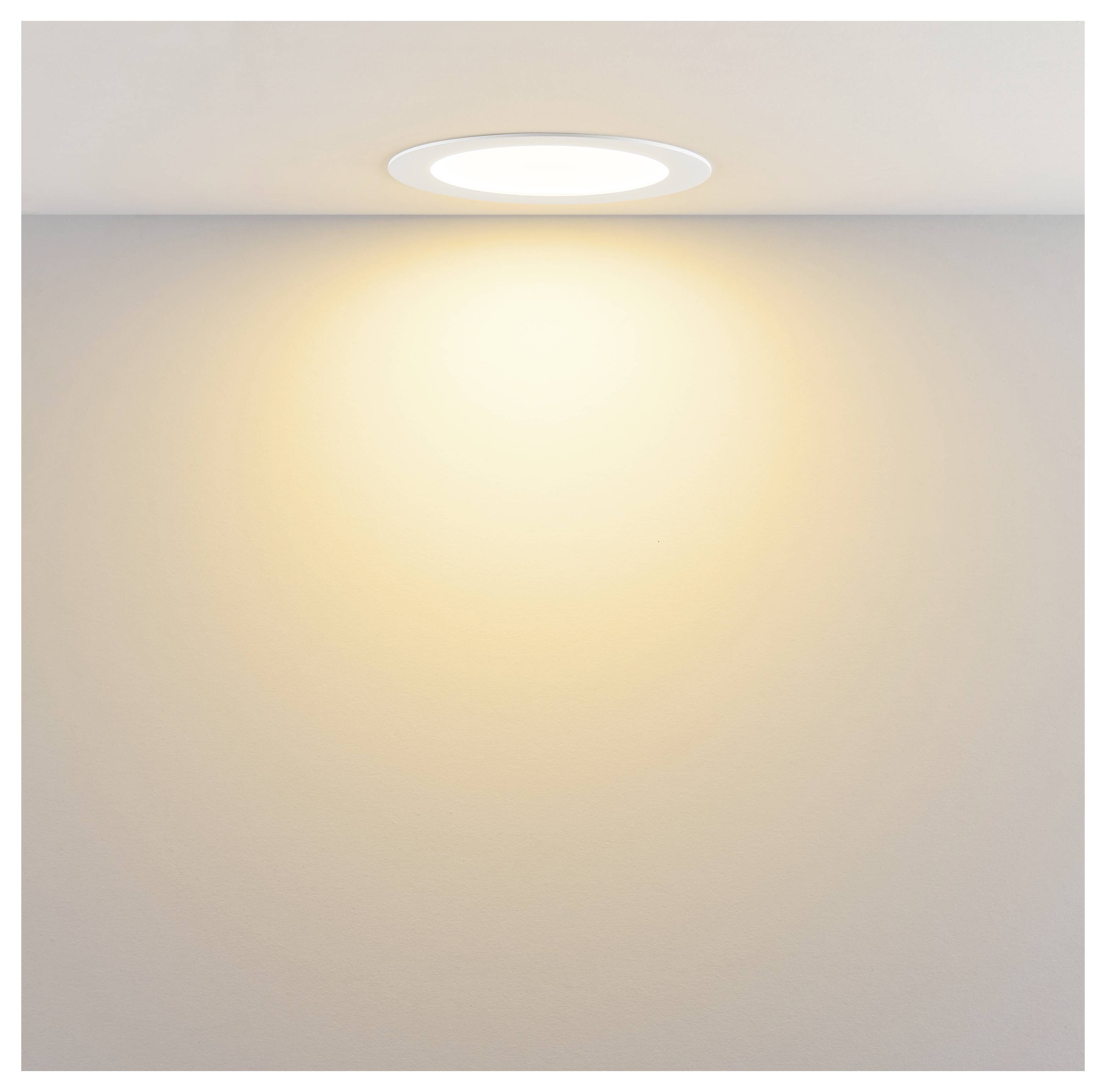 An der Decke montierte runde Einbauleuchte, die ein warmes Licht auf eine schlichte Wand wirft.